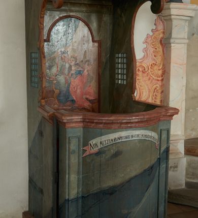 Zdjęcie nr 3: Konfesjonał na rzucie prostokąta zamkniętego od przodu łukiem segmentowym nadwieszonym, ustawiony na profilowanym cokole. Wybrzuszone przedpiersie ujęte lizenami z płycinami, zamknięte profilowanym gzymsem, u góry głównego pola przedpiersia namalowana banderola z napisem „NON MULTUM AB IMPECCABILI DISCEDIT, QVI PECCATUM UT DECET FATETUR. Aristoteles.”. Zaplecek z płyciną w polu w formie stojącego prostokąta zamkniętego łukiem półkolistym nadwieszonym, o wklęsłym dolnym odcinku. W polu malowana scena spowiedzi królowej u św. Jana Nepomucena. W lewej części sceny święty ukazany w pozycji siedzącej, na fotelu, prawą ręką wspiera się na podłokietniku, lewą podpiera głowę. Ubrany jest w sutannę, komżę, na ramionach ma stułę, a na głowie biret. W prawej części sceny ukazana jest klęcząca królowa, z lewą ręką złożoną na piersi, prawą wyciągniętą do góry. Ubrana jest w długą suknię, dołem czerwoną, w górnej części niebieską, przepasaną w talii, jasnobrązowy płaszcz, na głowie ma koronę otwartą. Scena ukazana jest we wnętrzu, w górnej części, po lewej, podwieszona zielona kurtyna. W dolnym podłuczu płyciny napis: „Solve Vincula Colli tui Captiva Filia / Sion. Ecclesia St 52”. 
Zaplecek ujęty ściankami bocznymi, w dolnej połowie szerokimi, zamkniętymi profilowanym gzymsem stanowiącym kontynuację gzymsu wieńczącego przedpiersie, z prostokątnymi drzwiczkami na zawiasach z lewej strony. W górnej połowie ścianki są węższe, o fantazyjnym wykroju, zakończone wolutą, z prostokątnymi prześwitami wypełnionymi kratką. Całość zwieńczona jest baldachimem na tym samym rzucie co korpus, ujętym z trzech stron belkowaniem. W partii frontowej fryzu malowana banderola z napisem: „PECCAVIMUS, INIQVITATEM FECIMUS, IMPIE EGIMUS. Danielis 9.”. Na podniebieniu baldachimu płycina w kształcie kwadratu wpisanego w czteroliść. W polu malowane przedstawienie aniołka w locie, który w prawej ręce trzyma język oraz liść palmy, w lewej zaś wieniec laurowy i kłódkę. Struktura konfesjonału polichromowana w sposób imitujący marmur w kolorze zielono-niebieskim, cokół, gzymsy i profile polichromowana w sposób imitujący marmur w kolorze jasnoczerwonym. 
