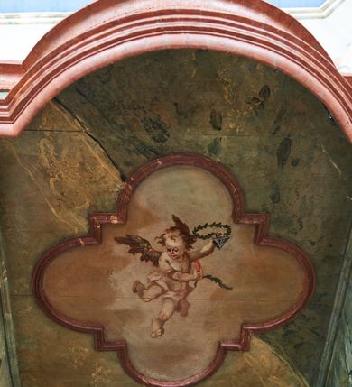 Zdjęcie nr 10: Konfesjonał na rzucie prostokąta zamkniętego od przodu łukiem segmentowym nadwieszonym, ustawiony na profilowanym cokole. Wybrzuszone przedpiersie ujęte lizenami z płycinami, zamknięte profilowanym gzymsem, u góry głównego pola przedpiersia namalowana banderola z napisem „NON MULTUM AB IMPECCABILI DISCEDIT, QVI PECCATUM UT DECET FATETUR. Aristoteles.”. Zaplecek z płyciną w polu w formie stojącego prostokąta zamkniętego łukiem półkolistym nadwieszonym, o wklęsłym dolnym odcinku. W polu malowana scena spowiedzi królowej u św. Jana Nepomucena. W lewej części sceny święty ukazany w pozycji siedzącej, na fotelu, prawą ręką wspiera się na podłokietniku, lewą podpiera głowę. Ubrany jest w sutannę, komżę, na ramionach ma stułę, a na głowie biret. W prawej części sceny ukazana jest klęcząca królowa, z lewą ręką złożoną na piersi, prawą wyciągniętą do góry. Ubrana jest w długą suknię, dołem czerwoną, w górnej części niebieską, przepasaną w talii, jasnobrązowy płaszcz, na głowie ma koronę otwartą. Scena ukazana jest we wnętrzu, w górnej części, po lewej, podwieszona zielona kurtyna. W dolnym podłuczu płyciny napis: „Solve Vincula Colli tui Captiva Filia / Sion. Ecclesia St 52”. 
Zaplecek ujęty ściankami bocznymi, w dolnej połowie szerokimi, zamkniętymi profilowanym gzymsem stanowiącym kontynuację gzymsu wieńczącego przedpiersie, z prostokątnymi drzwiczkami na zawiasach z lewej strony. W górnej połowie ścianki są węższe, o fantazyjnym wykroju, zakończone wolutą, z prostokątnymi prześwitami wypełnionymi kratką. Całość zwieńczona jest baldachimem na tym samym rzucie co korpus, ujętym z trzech stron belkowaniem. W partii frontowej fryzu malowana banderola z napisem: „PECCAVIMUS, INIQVITATEM FECIMUS, IMPIE EGIMUS. Danielis 9.”. Na podniebieniu baldachimu płycina w kształcie kwadratu wpisanego w czteroliść. W polu malowane przedstawienie aniołka w locie, który w prawej ręce trzyma język oraz liść palmy, w lewej zaś wieniec laurowy i kłódkę. Struktura konfesjonału polichromowana w sposób imitujący marmur w kolorze zielono-niebieskim, cokół, gzymsy i profile polichromowana w sposób imitujący marmur w kolorze jasnoczerwonym. 
