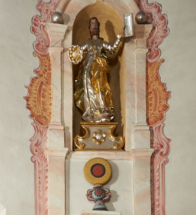 Zdjęcie nr 1: W narożach ośmiobocznej kaplicy Matki Boskiej Karmelitańskiej znajduje się osiem nisz z siedziskami, ujętych parami pilastrów podtrzymujących archiwoltę z kluczem, pod ich łukami podwieszone figury proroków, na kluczu i głowicach pilastrów ustawione wazony ze słonecznikami. Nad nimi, na wysokim cokole mniejsze, analogiczne nisze z figurami świętych stojącymi na cokołach. Architektoniczna konstrukcja ujęta malowanym rocaille&#039;m. 
Figury proroków podwieszone w dolnych niszach mają ugięte nogi i rozłożone na boki ręce, w których trzymają banderole. Przedstawieni są jako starcy z długimi brodami lub jako dojrzali mężczyźni z krótkimi. Figury Dawida i Salomona ukazane są w strojach królewskich, z koronami na głowach. Rzeźba Balaama przedstawiona jest w tunice i płaszczu, z głową oślicy przy nodze. Melchizedek jest w stroju kapłańskim, z albą, komżą i stułą. Elizeusz ubrany jest w tunikę i płaszcz, na głowie ma turban, a przy nodze głowę wołu. Pozostałe figury pozbawione atrybutów, ukazane są w tunikach i płaszczach lub szatach spodnich i wierzchnich. 
Figury świętych z górnego rzędu nisz ustawione są na cokołach i na rzeźbionych podstawach w formie obłoków, ujętych spływami wolutowymi, dekorowanymi rozetami z przodu. Rzeźby ukazane są frontalnie lub zwrócone trzy czwarte w bok, ręce mają rozłożone na boki lub jedną złożona na piersi. Ukazani są jako dojrzali mężczyźni z krótkimi kręconymi brodami i kręconymi włosami opadającymi na ramiona. Ubrani są w tuniki przylegające do ciała oraz płaszcze. Wyłącznie część figur posiada atrybuty. Święty Juda Tadeusz ukazany jest z pałką, św. Bartłomiej z płaszczem z ludzką twarzą (skóra), św. Szymon z piłą, św. Filip z kamieniami w dłoni, św. Maciej lub św. Tomasz z włócznią oraz św. Jakub Mniejszy z rozetą i księgą.  
Figury polichromowane są naturalistycznie w partiach ciała, szaty i atrybuty są złocone, srebrzone, laserowane lub polichromowane. 