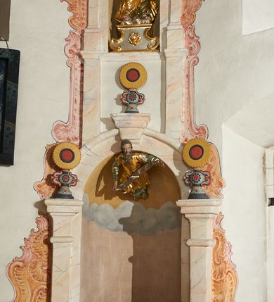 Zdjęcie nr 6: W narożach ośmiobocznej kaplicy Matki Boskiej Karmelitańskiej znajduje się osiem nisz z siedziskami, ujętych parami pilastrów podtrzymujących archiwoltę z kluczem, pod ich łukami podwieszone figury proroków, na kluczu i głowicach pilastrów ustawione wazony ze słonecznikami. Nad nimi, na wysokim cokole mniejsze, analogiczne nisze z figurami świętych stojącymi na cokołach. Architektoniczna konstrukcja ujęta malowanym rocaille'm. 
Figury proroków podwieszone w dolnych niszach mają ugięte nogi i rozłożone na boki ręce, w których trzymają banderole. Przedstawieni są jako starcy z długimi brodami lub jako dojrzali mężczyźni z krótkimi. Figury Dawida i Salomona ukazane są w strojach królewskich, z koronami na głowach. Rzeźba Balaama przedstawiona jest w tunice i płaszczu, z głową oślicy przy nodze. Melchizedek jest w stroju kapłańskim, z albą, komżą i stułą. Elizeusz ubrany jest w tunikę i płaszcz, na głowie ma turban, a przy nodze głowę wołu. Pozostałe figury pozbawione atrybutów, ukazane są w tunikach i płaszczach lub szatach spodnich i wierzchnich. 
Figury świętych z górnego rzędu nisz ustawione są na cokołach i na rzeźbionych podstawach w formie obłoków, ujętych spływami wolutowymi, dekorowanymi rozetami z przodu. Rzeźby ukazane są frontalnie lub zwrócone trzy czwarte w bok, ręce mają rozłożone na boki lub jedną złożona na piersi. Ukazani są jako dojrzali mężczyźni z krótkimi kręconymi brodami i kręconymi włosami opadającymi na ramiona. Ubrani są w tuniki przylegające do ciała oraz płaszcze. Wyłącznie część figur posiada atrybuty. Święty Juda Tadeusz ukazany jest z pałką, św. Bartłomiej z płaszczem z ludzką twarzą (skóra), św. Szymon z piłą, św. Filip z kamieniami w dłoni, św. Maciej lub św. Tomasz z włócznią oraz św. Jakub Mniejszy z rozetą i księgą.  
Figury polichromowane są naturalistycznie w partiach ciała, szaty i atrybuty są złocone, srebrzone, laserowane lub polichromowane. 