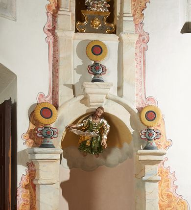 Zdjęcie nr 3: W narożach ośmiobocznej kaplicy Matki Boskiej Karmelitańskiej znajduje się osiem nisz z siedziskami, ujętych parami pilastrów podtrzymujących archiwoltę z kluczem, pod ich łukami podwieszone figury proroków, na kluczu i głowicach pilastrów ustawione wazony ze słonecznikami. Nad nimi, na wysokim cokole mniejsze, analogiczne nisze z figurami świętych stojącymi na cokołach. Architektoniczna konstrukcja ujęta malowanym rocaille'm. 
Figury proroków podwieszone w dolnych niszach mają ugięte nogi i rozłożone na boki ręce, w których trzymają banderole. Przedstawieni są jako starcy z długimi brodami lub jako dojrzali mężczyźni z krótkimi. Figury Dawida i Salomona ukazane są w strojach królewskich, z koronami na głowach. Rzeźba Balaama przedstawiona jest w tunice i płaszczu, z głową oślicy przy nodze. Melchizedek jest w stroju kapłańskim, z albą, komżą i stułą. Elizeusz ubrany jest w tunikę i płaszcz, na głowie ma turban, a przy nodze głowę wołu. Pozostałe figury pozbawione atrybutów, ukazane są w tunikach i płaszczach lub szatach spodnich i wierzchnich. 
Figury świętych z górnego rzędu nisz ustawione są na cokołach i na rzeźbionych podstawach w formie obłoków, ujętych spływami wolutowymi, dekorowanymi rozetami z przodu. Rzeźby ukazane są frontalnie lub zwrócone trzy czwarte w bok, ręce mają rozłożone na boki lub jedną złożona na piersi. Ukazani są jako dojrzali mężczyźni z krótkimi kręconymi brodami i kręconymi włosami opadającymi na ramiona. Ubrani są w tuniki przylegające do ciała oraz płaszcze. Wyłącznie część figur posiada atrybuty. Święty Juda Tadeusz ukazany jest z pałką, św. Bartłomiej z płaszczem z ludzką twarzą (skóra), św. Szymon z piłą, św. Filip z kamieniami w dłoni, św. Maciej lub św. Tomasz z włócznią oraz św. Jakub Mniejszy z rozetą i księgą.  
Figury polichromowane są naturalistycznie w partiach ciała, szaty i atrybuty są złocone, srebrzone, laserowane lub polichromowane. 