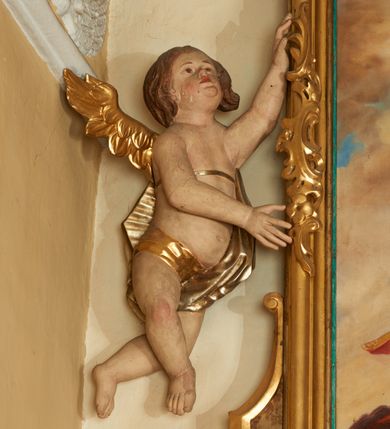 Zdjęcie nr 3: Obraz w formie stojącego prostokąta, ujęty profilowaną ramą, dekorowaną szczytem utworzonym z rocaille'owego kartusza z monogramem Marii w polu, flankowanym rocaille'm i kwiatami, podtrzymywanym w narożach konsolami. U dołu ramy podwieszenie utworzone z rocaille'owego kartusza z napisem „S(ANTA) MARIA / ORA PRO NOBIS”, ujęte rocaille'm i konsolami w narożach. Po bokach ramę trzymają nadlatujące putta. W centralnej części obrazu Matka Boska ukazana w pozycji stojącej pośród obłoków, z pochyloną głową i rozłożonymi na boki rękami podtrzymującymi płaszcz. Ubrana jest w różową suknię, przepasaną w talii, na ramionach ma obszerny, niebieski płaszcz, wokół głowy zawiązaną jasnobrązową chustę, na głowie koronę otwartą. W dolnej części kompozycji ukazane dwie grupy klęczących świętych, zwróconych do wewnątrz. Po lewej tronie św. Piotr. św. Stanisław i św. Stefan (?). Na pierwszym planie św. Stefan ukazany z profilu, z wyciągniętą w przód prawą ręką. Okolony jest krótką brodą i długimi, brązowymi włosami, ubrany w czerwony płaszcz królewski, ze złoconym wzorem, obszyty futrem. Przed nim na różowej poduszce z chwostami leży korona i jabłko królewskie. Obok niego św. Stanisław pozbawiony brody, w stroju biskupim, w żółtej kapie i infule oraz św. Piotr ukazany jako strzec, okolony siwymi włosami i brodą, w żółtym płaszczu. Po prawej stronie obrazu klęczą św. zakonnica, św. Katarzyna Aleksandryjska i św. Elżbieta Węgierska. Zakonnica ubrana jest w brązowy habit i welon oraz białą podwikę, prawą ręką przytrzymuje białą flagę, lewą wyciąga w bok. Obok niej klęczy św. Katarzyna z rekami złożonymi w geście modlitwy, o długich jasnych włosach. Ubrana jest w różowy płaszcz, na głowie ma koronę otwartą. Obok niej leży fragment koła. Za nimi postać św. Elżbiety, która podtrzymuje kwiaty róż. Ubrana jest w zielony płaszcz, na głowie ma czarny welon i koronę otwartą. Scena ukazana na tle jasnobłękitnego nieba wypełnionego żółto-brązowymi obłokami. W górnej części obrazu ukazane trzy putta. W dolnej części obrazu napis: „FUNDATORZY / MYSLIWIEC LUDWIK. IGLAR MACIEJ. GURCZYK PAWEŁ”. W prawym dolnym narożu obrazu sygnatura: „MAL(OWAŁ) KÛC ANTONI / 1932.”
