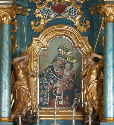 Zdjęcie nr 16: Ołtarz drewniany, prostopadłościenny z drewnianą mensą, w polu antepedium malowana na drewnie scena Zwiastowania (kopia obrazu Leonarda da Vinci). Na ołtarzu stoi tabliczka z kanonem w otoczeniu akantowych wolut tworzących podstawę dla pięciu lichtarzy utworzonych z ornamentu roślinnego. 
Nastawa architektoniczna, jednoosiowa, jednokondygnacyjna ze zwieńczeniem, ustawiona na dwustrefowym cokole, ujęta parą półfilarów i stojącą przed nimi parą kolumn dźwigających pełne belkowanie, przerwane nad polem środkowym. Na cokołach kolumn kanony w ornamentalnych ramach. Kolumny flankują od zewnątrz figury św. Tomasza (?) i św. Jana Nepomucena, od wewnątrz św. Michała Archanioła i św. Jerzego. W polu głównym obraz Matki Boskiej Szkaplerznej w formie stojącego prostokąta zamkniętego łukiem półkolistym nadwieszonym z uskokiem w profilowanej, dekorowanej ornamentem roślinnym ramie. Ponad nim kartusz ujęty ornamentem rocaille'owym i kratką regencyjną oraz uskrzydloną główką anielską flankowaną rocaille'ami. Zwieńczenie w formie leżącego prostokąta ujętego spływami wolutowymi dekorowanymi rocaille'ami, zamkniętego fragmentem falującego gzymsu z monogramem Marii w otoku z obłoków w glorii promienistej. W polu rzeźbiarskie przedstawienie św. Katarzyny Aleksandryjskiej flankowanej obłokami i wiązkami promieni oraz parą puttów. Na belkowaniu figury św. Rozalii i św. Calamindy. Ołtarz ujęty uszami utworzonymi z ornamentu rocaille'owego i kratki regencyjnej. Struktura polichromowana w sposób naśladujący marmoryzację w kolorze niebiesko-białym, profile i ornamentyka pozłacane.