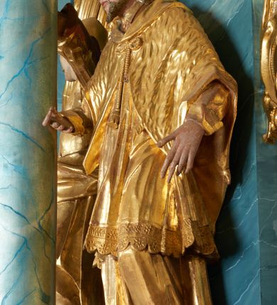 Zdjęcie nr 8: Ołtarz drewniany, prostopadłościenny z drewnianą mensą, w polu antepedium malowana na drewnie scena Zwiastowania (kopia obrazu Leonarda da Vinci). Na ołtarzu stoi tabliczka z kanonem w otoczeniu akantowych wolut tworzących podstawę dla pięciu lichtarzy utworzonych z ornamentu roślinnego. 
Nastawa architektoniczna, jednoosiowa, jednokondygnacyjna ze zwieńczeniem, ustawiona na dwustrefowym cokole, ujęta parą półfilarów i stojącą przed nimi parą kolumn dźwigających pełne belkowanie, przerwane nad polem środkowym. Na cokołach kolumn kanony w ornamentalnych ramach. Kolumny flankują od zewnątrz figury św. Tomasza (?) i św. Jana Nepomucena, od wewnątrz św. Michała Archanioła i św. Jerzego. W polu głównym obraz Matki Boskiej Szkaplerznej w formie stojącego prostokąta zamkniętego łukiem półkolistym nadwieszonym z uskokiem w profilowanej, dekorowanej ornamentem roślinnym ramie. Ponad nim kartusz ujęty ornamentem rocaille'owym i kratką regencyjną oraz uskrzydloną główką anielską flankowaną rocaille'ami. Zwieńczenie w formie leżącego prostokąta ujętego spływami wolutowymi dekorowanymi rocaille'ami, zamkniętego fragmentem falującego gzymsu z monogramem Marii w otoku z obłoków w glorii promienistej. W polu rzeźbiarskie przedstawienie św. Katarzyny Aleksandryjskiej flankowanej obłokami i wiązkami promieni oraz parą puttów. Na belkowaniu figury św. Rozalii i św. Calamindy. Ołtarz ujęty uszami utworzonymi z ornamentu rocaille'owego i kratki regencyjnej. Struktura polichromowana w sposób naśladujący marmoryzację w kolorze niebiesko-białym, profile i ornamentyka pozłacane.