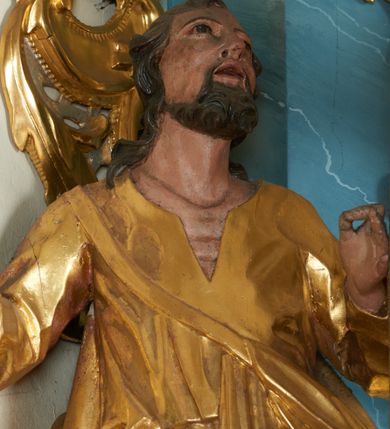 Zdjęcie nr 7: Ołtarz drewniany, prostopadłościenny z drewnianą mensą, w polu antepedium malowana na drewnie scena Zwiastowania (kopia obrazu Leonarda da Vinci). Na ołtarzu stoi tabliczka z kanonem w otoczeniu akantowych wolut tworzących podstawę dla pięciu lichtarzy utworzonych z ornamentu roślinnego. 
Nastawa architektoniczna, jednoosiowa, jednokondygnacyjna ze zwieńczeniem, ustawiona na dwustrefowym cokole, ujęta parą półfilarów i stojącą przed nimi parą kolumn dźwigających pełne belkowanie, przerwane nad polem środkowym. Na cokołach kolumn kanony w ornamentalnych ramach. Kolumny flankują od zewnątrz figury św. Tomasza (?) i św. Jana Nepomucena, od wewnątrz św. Michała Archanioła i św. Jerzego. W polu głównym obraz Matki Boskiej Szkaplerznej w formie stojącego prostokąta zamkniętego łukiem półkolistym nadwieszonym z uskokiem w profilowanej, dekorowanej ornamentem roślinnym ramie. Ponad nim kartusz ujęty ornamentem rocaille'owym i kratką regencyjną oraz uskrzydloną główką anielską flankowaną rocaille'ami. Zwieńczenie w formie leżącego prostokąta ujętego spływami wolutowymi dekorowanymi rocaille'ami, zamkniętego fragmentem falującego gzymsu z monogramem Marii w otoku z obłoków w glorii promienistej. W polu rzeźbiarskie przedstawienie św. Katarzyny Aleksandryjskiej flankowanej obłokami i wiązkami promieni oraz parą puttów. Na belkowaniu figury św. Rozalii i św. Calamindy. Ołtarz ujęty uszami utworzonymi z ornamentu rocaille'owego i kratki regencyjnej. Struktura polichromowana w sposób naśladujący marmoryzację w kolorze niebiesko-białym, profile i ornamentyka pozłacane.