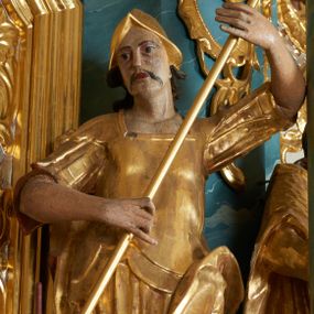 Zdjęcie nr 1: Figura ścięta z tyłu, drążona, zwrócona frontalnie, z głową lekko skierowaną w lewo, w kontrapoście. Święty obiema rękami trzyma włócznię skierowaną w stronę smoka, leżącego u jego stóp. Twarz ma pociągłą, o zapadniętych policzkach, oczach migdałowatych, nosie lekko garbatym, ustach pełnych, okoloną wąskimi, długimi wąsami, włosy długie, silnie kręcone, opadające na plecy. Ubrany jest w strój żołnierza: tunikę sięgającą kolan, rzymską zbroję z piórami oraz płaszcz narzucony na plecy i opadający na lewą nogę, na głowie ma hełm. Ciało polichromowane naturalistycznie, strój złocony.
