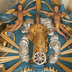 Zdjęcie nr 1: Figura ścięta z tyłu. Święta przedstawiona jest w całej postaci, stoi frontalnie, w delikatnym kontrapoście, z wysuniętym w bok lewym biodrem. Obie ręce ma ugięte i wyciągnięte w przód. Jej twarz jest pociągła o pełnych policzkach, z uwypukloną brodą i podbródkiem oraz niskim czołem. Oczy ma migdałowate, nos prosty, usta pełne, lekko rozchylone. Jej twarz jest okolona długimi, mocno falowanymi włosami opadającymi na plecy. Święta ubrana jest w suknię z dekoltem, spiętą gorsetem w talii oraz płaszcz zapięty na piersi i opadający na boki postaci, z fragmentem tkaniny zawiniętym na jej prawej nodze. Na głowie ma koronę otwartą, na szyi i nadgarstku biżuterię. Przed figurą znajduje się koło. Polichromia naturalistyczna w partiach ciała, strój złocony, koło srebrzone.