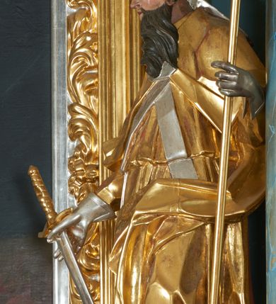 Zdjęcie nr 13: Ołtarz drewniany, prostopadłościenny z drewnianą mensą, w polu antepedium malowana na drewnie scena Ukrzyżowania. Na ołtarzu stoi tabliczka z kanonem w otoczeniu akantowych wolut tworzących podstawę dla pięciu lichtarzy utworzonych z ornamentu roślinnego (brak środkowego). 
Nastawa architektoniczna, jednoosiowa, jednokondygnacyjna ze zwieńczeniem, ustawiona na dwustrefowym cokole, ujęta parą półfilarów i stojącą przed nimi parą kolumn dźwigających pełne belkowanie, przerwane nad polem środkowym. Na cokołach kolumn kanony w ornamentalnych ramach. Kolumny flankują od zewnątrz figury św. Floriana i św. Longina, od wewnątrz św. Donata i św. Marcina. W polu głównym obraz Ukrzyżowania w formie stojącego prostokąta zamkniętego łukiem półkolistym nadwieszonym z uskokiem w profilowanej, dekorowanej ornamentem roślinnym ramie. Ponad nim kartusz ujęty ornamentem rocaille&#039;owym i kratką regencyjną oraz uskrzydlona główka anielska flankowana rocaille&#039;ami. Zwieńczenie w formie leżącego prostokąta ujętego spływami wolutowymi dekorowanymi rocaille&#039;ami, zamkniętego fragmentem falującego gzymsu z monogramem IHS w otoku z obłoków w glorii promienistej. W polu rzeźbiarskie przedstawienie św. Antoniego Padewskiego flankowanego obłokami i wiązkami promieni oraz parą puttów. Na belkowaniu figury św. Walentego i św. Jana Chryzostoma. Ołtarz ujęty uszami utworzonymi z ornamentu rocaille&#039;owego i kratki regencyjnej. Struktura polichromowana w sposób naśladujący marmoryzację w kolorze niebiesko-białym, profile i ornamentyka pozłacane.