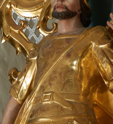 Zdjęcie nr 3: Ołtarz drewniany, prostopadłościenny z drewnianą mensą, w polu antepedium malowana na drewnie scena Ukrzyżowania. Na ołtarzu stoi tabliczka z kanonem w otoczeniu akantowych wolut tworzących podstawę dla pięciu lichtarzy utworzonych z ornamentu roślinnego (brak środkowego). 
Nastawa architektoniczna, jednoosiowa, jednokondygnacyjna ze zwieńczeniem, ustawiona na dwustrefowym cokole, ujęta parą półfilarów i stojącą przed nimi parą kolumn dźwigających pełne belkowanie, przerwane nad polem środkowym. Na cokołach kolumn kanony w ornamentalnych ramach. Kolumny flankują od zewnątrz figury św. Floriana i św. Longina, od wewnątrz św. Donata i św. Marcina. W polu głównym obraz Ukrzyżowania w formie stojącego prostokąta zamkniętego łukiem półkolistym nadwieszonym z uskokiem w profilowanej, dekorowanej ornamentem roślinnym ramie. Ponad nim kartusz ujęty ornamentem rocaille&#039;owym i kratką regencyjną oraz uskrzydlona główka anielska flankowana rocaille&#039;ami. Zwieńczenie w formie leżącego prostokąta ujętego spływami wolutowymi dekorowanymi rocaille&#039;ami, zamkniętego fragmentem falującego gzymsu z monogramem IHS w otoku z obłoków w glorii promienistej. W polu rzeźbiarskie przedstawienie św. Antoniego Padewskiego flankowanego obłokami i wiązkami promieni oraz parą puttów. Na belkowaniu figury św. Walentego i św. Jana Chryzostoma. Ołtarz ujęty uszami utworzonymi z ornamentu rocaille&#039;owego i kratki regencyjnej. Struktura polichromowana w sposób naśladujący marmoryzację w kolorze niebiesko-białym, profile i ornamentyka pozłacane.