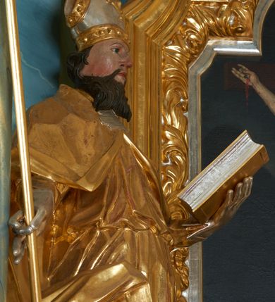 Zdjęcie nr 11: Ołtarz drewniany, prostopadłościenny z drewnianą mensą, w polu antepedium malowana na drewnie scena Ukrzyżowania. Na ołtarzu stoi tabliczka z kanonem w otoczeniu akantowych wolut tworzących podstawę dla pięciu lichtarzy utworzonych z ornamentu roślinnego (brak środkowego). 
Nastawa architektoniczna, jednoosiowa, jednokondygnacyjna ze zwieńczeniem, ustawiona na dwustrefowym cokole, ujęta parą półfilarów i stojącą przed nimi parą kolumn dźwigających pełne belkowanie, przerwane nad polem środkowym. Na cokołach kolumn kanony w ornamentalnych ramach. Kolumny flankują od zewnątrz figury św. Floriana i św. Longina, od wewnątrz św. Donata i św. Marcina. W polu głównym obraz Ukrzyżowania w formie stojącego prostokąta zamkniętego łukiem półkolistym nadwieszonym z uskokiem w profilowanej, dekorowanej ornamentem roślinnym ramie. Ponad nim kartusz ujęty ornamentem rocaille'owym i kratką regencyjną oraz uskrzydlona główka anielska flankowana rocaille'ami. Zwieńczenie w formie leżącego prostokąta ujętego spływami wolutowymi dekorowanymi rocaille'ami, zamkniętego fragmentem falującego gzymsu z monogramem IHS w otoku z obłoków w glorii promienistej. W polu rzeźbiarskie przedstawienie św. Antoniego Padewskiego flankowanego obłokami i wiązkami promieni oraz parą puttów. Na belkowaniu figury św. Walentego i św. Jana Chryzostoma. Ołtarz ujęty uszami utworzonymi z ornamentu rocaille'owego i kratki regencyjnej. Struktura polichromowana w sposób naśladujący marmoryzację w kolorze niebiesko-białym, profile i ornamentyka pozłacane.