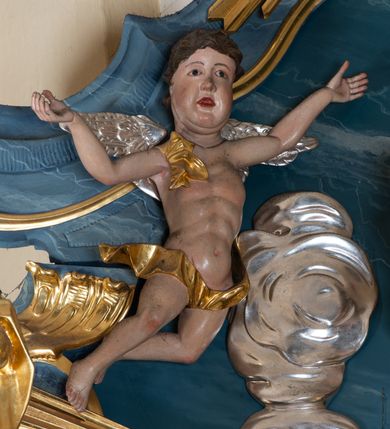 Zdjęcie nr 3: Figura ścięta z tyłu. Święty przedstawiony jest w całej postaci, frontalnie, w kontrapoście, delikatnie przechylony w tył. Lewą rękę zgiętą w łokciu wyciąga w przód, w prawej, zgiętej trzyma księgę, na której siedzi Dzieciątko. Twarz ma pociągłą, o pełnych policzkach, migdałowatych oczach, prostym nosie i pełnych ustach, z silnie zaznaczoną brodą i podbródkiem, okoloną krótkimi, kręconymi włosami. Święty ubrany jest w habit przewiązany w pasie podwójnym sznurem i pelerynkę. Nad jego głową nimb w formie glorii promienistej. Dzieciątko zwrócone jest profilem w prawo, lewą ręką ujmuje twarz świętego, prawą wyciąga w bok. Twarz ma pociągłą o pełnych policzkach, okoloną kręconymi włosami, ciało zaś ma szczupłe, w partii bioder przykryte tkaniną. Polichromia naturalistyczna w partiach ciała, szaty i gloria pozłocone.
