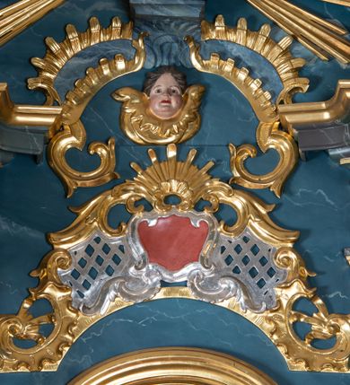 Zdjęcie nr 5: Figura ścięta z tyłu. Święty przedstawiony jest w całej postaci, frontalnie, w kontrapoście, delikatnie przechylony w tył. Lewą rękę zgiętą w łokciu wyciąga w przód, w prawej, zgiętej trzyma księgę, na której siedzi Dzieciątko. Twarz ma pociągłą, o pełnych policzkach, migdałowatych oczach, prostym nosie i pełnych ustach, z silnie zaznaczoną brodą i podbródkiem, okoloną krótkimi, kręconymi włosami. Święty ubrany jest w habit przewiązany w pasie podwójnym sznurem i pelerynkę. Nad jego głową nimb w formie glorii promienistej. Dzieciątko zwrócone jest profilem w prawo, lewą ręką ujmuje twarz świętego, prawą wyciąga w bok. Twarz ma pociągłą o pełnych policzkach, okoloną kręconymi włosami, ciało zaś ma szczupłe, w partii bioder przykryte tkaniną. Polichromia naturalistyczna w partiach ciała, szaty i gloria pozłocone.
