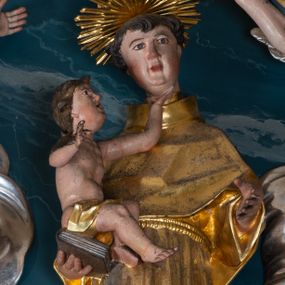 Zdjęcie nr 1: Figura ścięta z tyłu. Święty przedstawiony jest w całej postaci, frontalnie, w kontrapoście, delikatnie przechylony w tył. Lewą rękę zgiętą w łokciu wyciąga w przód, w prawej, zgiętej trzyma księgę, na której siedzi Dzieciątko. Twarz ma pociągłą, o pełnych policzkach, migdałowatych oczach, prostym nosie i pełnych ustach, z silnie zaznaczoną brodą i podbródkiem, okoloną krótkimi, kręconymi włosami. Święty ubrany jest w habit przewiązany w pasie podwójnym sznurem i pelerynkę. Nad jego głową nimb w formie glorii promienistej. Dzieciątko zwrócone jest profilem w prawo, lewą ręką ujmuje twarz świętego, prawą wyciąga w bok. Twarz ma pociągłą o pełnych policzkach, okoloną kręconymi włosami, ciało zaś ma szczupłe, w partii bioder przykryte tkaniną. Polichromia naturalistyczna w partiach ciała, szaty i gloria pozłocone.
