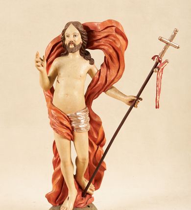 Zdjęcie nr 1: Rzeźba pełnoplastyczna, ustawiona na podstawie o nieregularnym planie, imitującej fragment podłoża. Chrystus ukazany frontalnie, w wykroku, w lewej wyciągniętej w bok ręce trzyma drzewce czerwonej, materiałowej chorągwi, zakończone krzyżem, prawą ugiętą, unosi w geście błogosławieństwa. Twarz ma szczupłą i pociągłą, o wąskich, migdałowatych oczach, szerokim nosie i niewielkich ustach; okoloną krótką brodą oraz silnie skręconymi w pukle włosami, opadającymi na ramiona. Chrystus w partii bioder przewiązany krótkim, przylegającym, srebrzonym perizonium. Przez prawe udo i lewe ramię ma przewiązany czerwony, silnie drapowany płaszcz, rozwiany półkoliście z tyłu postaci oraz opadający po bokach. Ciało Chrystusa szczupłe, niemal pozbawione modelunku. Polichromia ciała figury naturalistyczna, o jasnej karnacji. 



