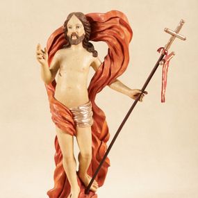 Zdjęcie nr 1: Rzeźba pełnoplastyczna, ustawiona na podstawie o nieregularnym planie, imitującej fragment podłoża. Chrystus ukazany frontalnie, w wykroku, w lewej wyciągniętej w bok ręce trzyma drzewce czerwonej, materiałowej chorągwi, zakończone krzyżem, prawą ugiętą, unosi w geście błogosławieństwa. Twarz ma szczupłą i pociągłą, o wąskich, migdałowatych oczach, szerokim nosie i niewielkich ustach; okoloną krótką brodą oraz silnie skręconymi w pukle włosami, opadającymi na ramiona. Chrystus w partii bioder przewiązany krótkim, przylegającym, srebrzonym perizonium. Przez prawe udo i lewe ramię ma przewiązany czerwony, silnie drapowany płaszcz, rozwiany półkoliście z tyłu postaci oraz opadający po bokach. Ciało Chrystusa szczupłe, niemal pozbawione modelunku. Polichromia ciała figury naturalistyczna, o jasnej karnacji. 



