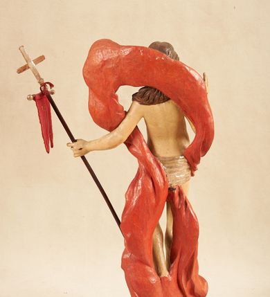 Zdjęcie nr 6: Rzeźba pełnoplastyczna, ustawiona na podstawie o nieregularnym planie, imitującej fragment podłoża. Chrystus ukazany frontalnie, w wykroku, w lewej wyciągniętej w bok ręce trzyma drzewce czerwonej, materiałowej chorągwi, zakończone krzyżem, prawą ugiętą, unosi w geście błogosławieństwa. Twarz ma szczupłą i pociągłą, o wąskich, migdałowatych oczach, szerokim nosie i niewielkich ustach; okoloną krótką brodą oraz silnie skręconymi w pukle włosami, opadającymi na ramiona. Chrystus w partii bioder przewiązany krótkim, przylegającym, srebrzonym perizonium. Przez prawe udo i lewe ramię ma przewiązany czerwony, silnie drapowany płaszcz, rozwiany półkoliście z tyłu postaci oraz opadający po bokach. Ciało Chrystusa szczupłe, niemal pozbawione modelunku. Polichromia ciała figury naturalistyczna, o jasnej karnacji. 



