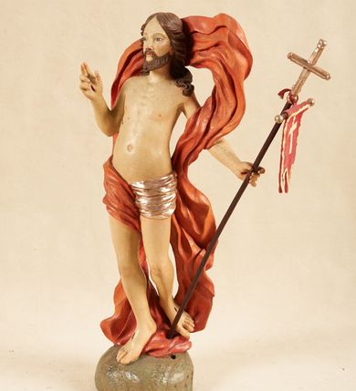 Zdjęcie nr 7: Rzeźba pełnoplastyczna, ustawiona na podstawie o nieregularnym planie, imitującej fragment podłoża. Chrystus ukazany frontalnie, w wykroku, w lewej wyciągniętej w bok ręce trzyma drzewce czerwonej, materiałowej chorągwi, zakończone krzyżem, prawą ugiętą, unosi w geście błogosławieństwa. Twarz ma szczupłą i pociągłą, o wąskich, migdałowatych oczach, szerokim nosie i niewielkich ustach; okoloną krótką brodą oraz silnie skręconymi w pukle włosami, opadającymi na ramiona. Chrystus w partii bioder przewiązany krótkim, przylegającym, srebrzonym perizonium. Przez prawe udo i lewe ramię ma przewiązany czerwony, silnie drapowany płaszcz, rozwiany półkoliście z tyłu postaci oraz opadający po bokach. Ciało Chrystusa szczupłe, niemal pozbawione modelunku. Polichromia ciała figury naturalistyczna, o jasnej karnacji. 




