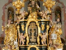 Zdjęcie nr 1: Ołtarz dwustronny, sarkofagowy, dekorowany rocaille'm, mensa drewniana na planie kwadratu, od frontu z kamiennym portatylem.
Nastawa ołtarzowa dwustronna, na rzucie leżącej litery X, w formie  rozbudowanego tabernakulum z tronem wystawienia. Obie strony są analogiczne pod względem architektonicznym. Tabernakulum na cokole, o wypukłej ściance frontowej, flankowanej parą pilastrów o trzonach dekorowanym płycinami z rocaille'm, dźwigających gzyms wieńczący. W polu drzwiczki ujęte rokokowym kartuszem. Na tabernakulum tron wystawienia o wklęsło-wypukłym licu, ujęty parą impostów podtrzymywanych przez rocaille'owe konsole oraz pilastrami w narożach, których trzony przyjmują formę spływów wolutowych, sięgające podstawy tabernakulum, na których stoją figury. W polu środkowym tronu wystawienia znajduje się obrotowa nisza o nieregularnym kształcie ujęta obramieniem z rocaille'u, przesłonięta wypukłą ścianką z płaskorzeźbionym krucyfiksem  i winnym gronem, zwieńczona rzeźbioną półpostacią. Całość wieńczy cokół z dwoma ramionami, na których stoją rocaille'owe wazony. Na cokole osadzona jest dużych rozmiarów, dwustronna, dwunastoramienna gwiazda relikwiarzowa, miażdżąca węża. Gwiazda z obu stron ujęta jest kilkoma pierścieniami z winnego grona oraz ornamentu roślinnego, w ramionach oraz w polu głównym umieszczone są za szkłem relikwie wśród kwiatowych dekoracji. 
Na awersie ołtarza, na mensie znajdują się dwie figurki puttów siedzących na obłokach i trzymających tabliczki z kanonami. Całość flankują ustawione na spływach wolutowych figury św. Jana Ewangelisty i św. Bartłomieja, tron wieńczy półpostać Boga Ojca, ujęta przez dwa putta z otwartymi księgami. Obrotową niszę flankują dwa aniołki trzymające lichtarze. Na rewersie ołtarza na spływach wolutowych stoją figury św. Andrzeja i św. Piotra, tron wieńczy półpostać Mojżesza flankowana przez dwa putta z otwartymi księgami.
Struktura polichromowana w kolorze ciemnozielonym, ornamentyka i profile złocone, detal srebrzony.
