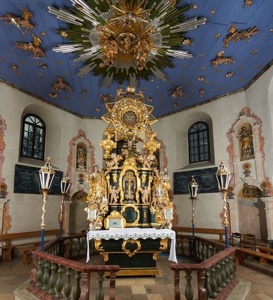 Zdjęcie nr 3: Ołtarz dwustronny, sarkofagowy, dekorowany rocaille'm, mensa drewniana na planie kwadratu, od frontu z kamiennym portatylem.
Nastawa ołtarzowa dwustronna, na rzucie leżącej litery X, w formie  rozbudowanego tabernakulum z tronem wystawienia. Obie strony są analogiczne pod względem architektonicznym. Tabernakulum na cokole, o wypukłej ściance frontowej, flankowanej parą pilastrów o trzonach dekorowanym płycinami z rocaille'm, dźwigających gzyms wieńczący. W polu drzwiczki ujęte rokokowym kartuszem. Na tabernakulum tron wystawienia o wklęsło-wypukłym licu, ujęty parą impostów podtrzymywanych przez rocaille'owe konsole oraz pilastrami w narożach, których trzony przyjmują formę spływów wolutowych, sięgające podstawy tabernakulum, na których stoją figury. W polu środkowym tronu wystawienia znajduje się obrotowa nisza o nieregularnym kształcie ujęta obramieniem z rocaille'u, przesłonięta wypukłą ścianką z płaskorzeźbionym krucyfiksem  i winnym gronem, zwieńczona rzeźbioną półpostacią. Całość wieńczy cokół z dwoma ramionami, na których stoją rocaille'owe wazony. Na cokole osadzona jest dużych rozmiarów, dwustronna, dwunastoramienna gwiazda relikwiarzowa, miażdżąca węża. Gwiazda z obu stron ujęta jest kilkoma pierścieniami z winnego grona oraz ornamentu roślinnego, w ramionach oraz w polu głównym umieszczone są za szkłem relikwie wśród kwiatowych dekoracji. 
Na awersie ołtarza, na mensie znajdują się dwie figurki puttów siedzących na obłokach i trzymających tabliczki z kanonami. Całość flankują ustawione na spływach wolutowych figury św. Jana Ewangelisty i św. Bartłomieja, tron wieńczy półpostać Boga Ojca, ujęta przez dwa putta z otwartymi księgami. Obrotową niszę flankują dwa aniołki trzymające lichtarze. Na rewersie ołtarza na spływach wolutowych stoją figury św. Andrzeja i św. Piotra, tron wieńczy półpostać Mojżesza flankowana przez dwa putta z otwartymi księgami.
Struktura polichromowana w kolorze ciemnozielonym, ornamentyka i profile złocone, detal srebrzony.
