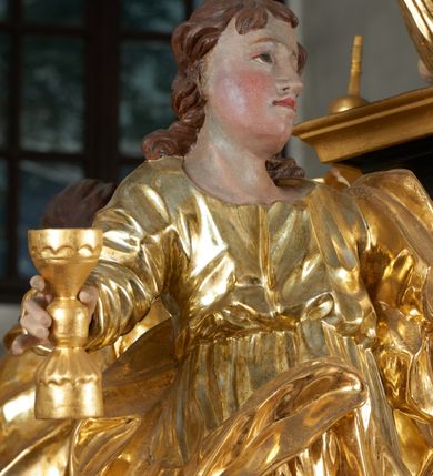 Zdjęcie nr 35: Ołtarz dwustronny, sarkofagowy, dekorowany rocaille'm, mensa drewniana na planie kwadratu, od frontu z kamiennym portatylem.
Nastawa ołtarzowa dwustronna, na rzucie leżącej litery X, w formie  rozbudowanego tabernakulum z tronem wystawienia. Obie strony są analogiczne pod względem architektonicznym. Tabernakulum na cokole, o wypukłej ściance frontowej, flankowanej parą pilastrów o trzonach dekorowanym płycinami z rocaille'm, dźwigających gzyms wieńczący. W polu drzwiczki ujęte rokokowym kartuszem. Na tabernakulum tron wystawienia o wklęsło-wypukłym licu, ujęty parą impostów podtrzymywanych przez rocaille'owe konsole oraz pilastrami w narożach, których trzony przyjmują formę spływów wolutowych, sięgające podstawy tabernakulum, na których stoją figury. W polu środkowym tronu wystawienia znajduje się obrotowa nisza o nieregularnym kształcie ujęta obramieniem z rocaille'u, przesłonięta wypukłą ścianką z płaskorzeźbionym krucyfiksem  i winnym gronem, zwieńczona rzeźbioną półpostacią. Całość wieńczy cokół z dwoma ramionami, na których stoją rocaille'owe wazony. Na cokole osadzona jest dużych rozmiarów, dwustronna, dwunastoramienna gwiazda relikwiarzowa, miażdżąca węża. Gwiazda z obu stron ujęta jest kilkoma pierścieniami z winnego grona oraz ornamentu roślinnego, w ramionach oraz w polu głównym umieszczone są za szkłem relikwie wśród kwiatowych dekoracji. 
Na awersie ołtarza, na mensie znajdują się dwie figurki puttów siedzących na obłokach i trzymających tabliczki z kanonami. Całość flankują ustawione na spływach wolutowych figury św. Jana Ewangelisty i św. Bartłomieja, tron wieńczy półpostać Boga Ojca, ujęta przez dwa putta z otwartymi księgami. Obrotową niszę flankują dwa aniołki trzymające lichtarze. Na rewersie ołtarza na spływach wolutowych stoją figury św. Andrzeja i św. Piotra, tron wieńczy półpostać Mojżesza flankowana przez dwa putta z otwartymi księgami.
Struktura polichromowana w kolorze ciemnozielonym, ornamentyka i profile złocone, detal srebrzony.
