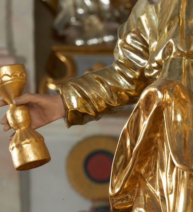 Zdjęcie nr 38: Ołtarz dwustronny, sarkofagowy, dekorowany rocaille&#039;m, mensa drewniana na planie kwadratu, od frontu z kamiennym portatylem.
Nastawa ołtarzowa dwustronna, na rzucie leżącej litery X, w formie  rozbudowanego tabernakulum z tronem wystawienia. Obie strony są analogiczne pod względem architektonicznym. Tabernakulum na cokole, o wypukłej ściance frontowej, flankowanej parą pilastrów o trzonach dekorowanym płycinami z rocaille&#039;m, dźwigających gzyms wieńczący. W polu drzwiczki ujęte rokokowym kartuszem. Na tabernakulum tron wystawienia o wklęsło-wypukłym licu, ujęty parą impostów podtrzymywanych przez rocaille&#039;owe konsole oraz pilastrami w narożach, których trzony przyjmują formę spływów wolutowych, sięgające podstawy tabernakulum, na których stoją figury. W polu środkowym tronu wystawienia znajduje się obrotowa nisza o nieregularnym kształcie ujęta obramieniem z rocaille&#039;u, przesłonięta wypukłą ścianką z płaskorzeźbionym krucyfiksem  i winnym gronem, zwieńczona rzeźbioną półpostacią. Całość wieńczy cokół z dwoma ramionami, na których stoją rocaille&#039;owe wazony. Na cokole osadzona jest dużych rozmiarów, dwustronna, dwunastoramienna gwiazda relikwiarzowa, miażdżąca węża. Gwiazda z obu stron ujęta jest kilkoma pierścieniami z winnego grona oraz ornamentu roślinnego, w ramionach oraz w polu głównym umieszczone są za szkłem relikwie wśród kwiatowych dekoracji. 
Na awersie ołtarza, na mensie znajdują się dwie figurki puttów siedzących na obłokach i trzymających tabliczki z kanonami. Całość flankują ustawione na spływach wolutowych figury św. Jana Ewangelisty i św. Bartłomieja, tron wieńczy półpostać Boga Ojca, ujęta przez dwa putta z otwartymi księgami. Obrotową niszę flankują dwa aniołki trzymające lichtarze. Na rewersie ołtarza na spływach wolutowych stoją figury św. Andrzeja i św. Piotra, tron wieńczy półpostać Mojżesza flankowana przez dwa putta z otwartymi księgami.
Struktura polichromowana w kolorze ciemnozielonym, ornamentyka i profile złocone, detal srebrzony.
