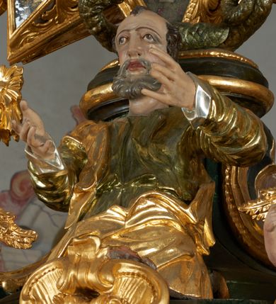 Zdjęcie nr 30: Ołtarz dwustronny, sarkofagowy, dekorowany rocaille&#039;m, mensa drewniana na planie kwadratu, od frontu z kamiennym portatylem.
Nastawa ołtarzowa dwustronna, na rzucie leżącej litery X, w formie  rozbudowanego tabernakulum z tronem wystawienia. Obie strony są analogiczne pod względem architektonicznym. Tabernakulum na cokole, o wypukłej ściance frontowej, flankowanej parą pilastrów o trzonach dekorowanym płycinami z rocaille&#039;m, dźwigających gzyms wieńczący. W polu drzwiczki ujęte rokokowym kartuszem. Na tabernakulum tron wystawienia o wklęsło-wypukłym licu, ujęty parą impostów podtrzymywanych przez rocaille&#039;owe konsole oraz pilastrami w narożach, których trzony przyjmują formę spływów wolutowych, sięgające podstawy tabernakulum, na których stoją figury. W polu środkowym tronu wystawienia znajduje się obrotowa nisza o nieregularnym kształcie ujęta obramieniem z rocaille&#039;u, przesłonięta wypukłą ścianką z płaskorzeźbionym krucyfiksem  i winnym gronem, zwieńczona rzeźbioną półpostacią. Całość wieńczy cokół z dwoma ramionami, na których stoją rocaille&#039;owe wazony. Na cokole osadzona jest dużych rozmiarów, dwustronna, dwunastoramienna gwiazda relikwiarzowa, miażdżąca węża. Gwiazda z obu stron ujęta jest kilkoma pierścieniami z winnego grona oraz ornamentu roślinnego, w ramionach oraz w polu głównym umieszczone są za szkłem relikwie wśród kwiatowych dekoracji. 
Na awersie ołtarza, na mensie znajdują się dwie figurki puttów siedzących na obłokach i trzymających tabliczki z kanonami. Całość flankują ustawione na spływach wolutowych figury św. Jana Ewangelisty i św. Bartłomieja, tron wieńczy półpostać Boga Ojca, ujęta przez dwa putta z otwartymi księgami. Obrotową niszę flankują dwa aniołki trzymające lichtarze. Na rewersie ołtarza na spływach wolutowych stoją figury św. Andrzeja i św. Piotra, tron wieńczy półpostać Mojżesza flankowana przez dwa putta z otwartymi księgami.
Struktura polichromowana w kolorze ciemnozielonym, ornamentyka i profile złocone, detal srebrzony.
