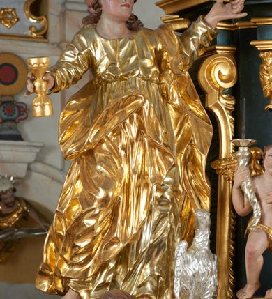 Zdjęcie nr 34: Ołtarz dwustronny, sarkofagowy, dekorowany rocaille'm, mensa drewniana na planie kwadratu, od frontu z kamiennym portatylem.
Nastawa ołtarzowa dwustronna, na rzucie leżącej litery X, w formie  rozbudowanego tabernakulum z tronem wystawienia. Obie strony są analogiczne pod względem architektonicznym. Tabernakulum na cokole, o wypukłej ściance frontowej, flankowanej parą pilastrów o trzonach dekorowanym płycinami z rocaille'm, dźwigających gzyms wieńczący. W polu drzwiczki ujęte rokokowym kartuszem. Na tabernakulum tron wystawienia o wklęsło-wypukłym licu, ujęty parą impostów podtrzymywanych przez rocaille'owe konsole oraz pilastrami w narożach, których trzony przyjmują formę spływów wolutowych, sięgające podstawy tabernakulum, na których stoją figury. W polu środkowym tronu wystawienia znajduje się obrotowa nisza o nieregularnym kształcie ujęta obramieniem z rocaille'u, przesłonięta wypukłą ścianką z płaskorzeźbionym krucyfiksem  i winnym gronem, zwieńczona rzeźbioną półpostacią. Całość wieńczy cokół z dwoma ramionami, na których stoją rocaille'owe wazony. Na cokole osadzona jest dużych rozmiarów, dwustronna, dwunastoramienna gwiazda relikwiarzowa, miażdżąca węża. Gwiazda z obu stron ujęta jest kilkoma pierścieniami z winnego grona oraz ornamentu roślinnego, w ramionach oraz w polu głównym umieszczone są za szkłem relikwie wśród kwiatowych dekoracji. 
Na awersie ołtarza, na mensie znajdują się dwie figurki puttów siedzących na obłokach i trzymających tabliczki z kanonami. Całość flankują ustawione na spływach wolutowych figury św. Jana Ewangelisty i św. Bartłomieja, tron wieńczy półpostać Boga Ojca, ujęta przez dwa putta z otwartymi księgami. Obrotową niszę flankują dwa aniołki trzymające lichtarze. Na rewersie ołtarza na spływach wolutowych stoją figury św. Andrzeja i św. Piotra, tron wieńczy półpostać Mojżesza flankowana przez dwa putta z otwartymi księgami.
Struktura polichromowana w kolorze ciemnozielonym, ornamentyka i profile złocone, detal srebrzony.
