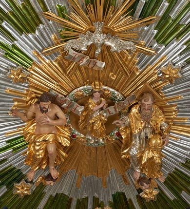 Zdjęcie nr 45: Ołtarz dwustronny, sarkofagowy, dekorowany rocaille&#039;m, mensa drewniana na planie kwadratu, od frontu z kamiennym portatylem.
Nastawa ołtarzowa dwustronna, na rzucie leżącej litery X, w formie  rozbudowanego tabernakulum z tronem wystawienia. Obie strony są analogiczne pod względem architektonicznym. Tabernakulum na cokole, o wypukłej ściance frontowej, flankowanej parą pilastrów o trzonach dekorowanym płycinami z rocaille&#039;m, dźwigających gzyms wieńczący. W polu drzwiczki ujęte rokokowym kartuszem. Na tabernakulum tron wystawienia o wklęsło-wypukłym licu, ujęty parą impostów podtrzymywanych przez rocaille&#039;owe konsole oraz pilastrami w narożach, których trzony przyjmują formę spływów wolutowych, sięgające podstawy tabernakulum, na których stoją figury. W polu środkowym tronu wystawienia znajduje się obrotowa nisza o nieregularnym kształcie ujęta obramieniem z rocaille&#039;u, przesłonięta wypukłą ścianką z płaskorzeźbionym krucyfiksem  i winnym gronem, zwieńczona rzeźbioną półpostacią. Całość wieńczy cokół z dwoma ramionami, na których stoją rocaille&#039;owe wazony. Na cokole osadzona jest dużych rozmiarów, dwustronna, dwunastoramienna gwiazda relikwiarzowa, miażdżąca węża. Gwiazda z obu stron ujęta jest kilkoma pierścieniami z winnego grona oraz ornamentu roślinnego, w ramionach oraz w polu głównym umieszczone są za szkłem relikwie wśród kwiatowych dekoracji. 
Na awersie ołtarza, na mensie znajdują się dwie figurki puttów siedzących na obłokach i trzymających tabliczki z kanonami. Całość flankują ustawione na spływach wolutowych figury św. Jana Ewangelisty i św. Bartłomieja, tron wieńczy półpostać Boga Ojca, ujęta przez dwa putta z otwartymi księgami. Obrotową niszę flankują dwa aniołki trzymające lichtarze. Na rewersie ołtarza na spływach wolutowych stoją figury św. Andrzeja i św. Piotra, tron wieńczy półpostać Mojżesza flankowana przez dwa putta z otwartymi księgami.
Struktura polichromowana w kolorze ciemnozielonym, ornamentyka i profile złocone, detal srebrzony.
