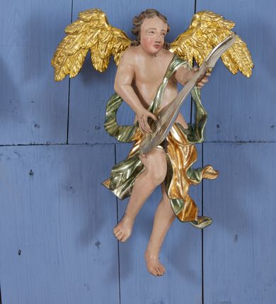 Zdjęcie nr 4: Drewniany, polichromowany na niebiesko strop, na planie ośmioboku, ujęty profilowaną ramą. W jego centrum grupa Koronacji Marii w glorii promienistej. W środku grupy figura Matki Boskiej na tle opaski dekorowanej kwiatami. Maria ukazana frontalnie, w kontrapoście, z rękami złożonymi w geście modlitwy. Twarz ma pociągłą, szczupłą, o młodzieńczych rysach, okoloną długimi włosami, upiętymi z tyłu głowy. Ubrana jest w srebrzoną suknię oraz złocony płaszcz narzucony na ramiona i zawinięty na lewej nodze, na głowie ma koronę zamkniętą. Marię flankują dwie banderole z napisem: „FIAT”. Po jej prawej znacznie większa figura Chrystusa, ukazanego frontalnie, w pozycji siedzącej, z głową skierowaną do wewnątrz; jego lewa ręka spoczywa na piersi, prawa jest ugięta i uniesiona w geście wskazującym. Twarz ma pociągłą, szczupłą, okoloną brodą skręconą w dwa pukle, oraz kręconymi włosami. Chrystus przewiązany jest w partii bioder złoconym płaszczem otaczającym postać i odsłaniającym lewą nogę. Jego ciało w odsłoniętych partiach, ma delikatnie zarysowaną muskulaturę, z zaznaczonymi śladami męki. Po lewej stronie Marii znacznie większa figura Boga Ojca, ukazanego frontalnie, w pozycji siedzącej. Lewą ręką przytrzymuje jabłko królewskie, w dłoni dzierży berło, prawą wyciąga w geście błogosławieństwa. Twarz ma pociągłą, o starczych rysach, okoloną długą, kręconą brodą opadającą na pierś oraz krótkimi włosami. Ubrany jest w obficie drapowaną srebrzoną tunikę, przepasaną w talii oraz złocony płaszcz z dekoracyjną, kameryzowaną lamówką, zapięty na piersi i opadający na boki, z zawiniętym fragmentem tkaniny na lewej nodze. Nad postaciami nadlatująca gołębica Ducha Świętego w glorii promienistej z banderolą z napisem: „FIAT”. Grupa na tle trzystrefowej glorii promienistej dekorowanej gwiazdami i uskrzydlonymi główkami anielskimi. Glorię z grupą Koronacji otacza dwunastu aniołów, ułożonych naprzemiennie w cztery pary muzykujących postaci (ze skrzypcami, wiolonczelą, gitarą, trąbką, harfą) z czterema aniołami podtrzymującymi tace z symbolicznymi przedmiotami (różaniec, wieniec laurowy, chleb (?), dyscyplina). Strop dekorowany jest w całości gwiazdami i uskrzydlonymi główkami anielskimi. Figury w partiach ciała polichromowane są naturalistycznie, ich szaty są złocone, srebrzone i laserowane; atrybuty są srebrzone. 

