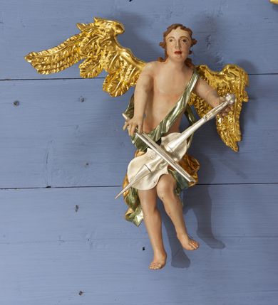 Zdjęcie nr 7: Drewniany, polichromowany na niebiesko strop, na planie ośmioboku, ujęty profilowaną ramą. W jego centrum grupa Koronacji Marii w glorii promienistej. W środku grupy figura Matki Boskiej na tle opaski dekorowanej kwiatami. Maria ukazana frontalnie, w kontrapoście, z rękami złożonymi w geście modlitwy. Twarz ma pociągłą, szczupłą, o młodzieńczych rysach, okoloną długimi włosami, upiętymi z tyłu głowy. Ubrana jest w srebrzoną suknię oraz złocony płaszcz narzucony na ramiona i zawinięty na lewej nodze, na głowie ma koronę zamkniętą. Marię flankują dwie banderole z napisem: „FIAT”. Po jej prawej znacznie większa figura Chrystusa, ukazanego frontalnie, w pozycji siedzącej, z głową skierowaną do wewnątrz; jego lewa ręka spoczywa na piersi, prawa jest ugięta i uniesiona w geście wskazującym. Twarz ma pociągłą, szczupłą, okoloną brodą skręconą w dwa pukle, oraz kręconymi włosami. Chrystus przewiązany jest w partii bioder złoconym płaszczem otaczającym postać i odsłaniającym lewą nogę. Jego ciało w odsłoniętych partiach, ma delikatnie zarysowaną muskulaturę, z zaznaczonymi śladami męki. Po lewej stronie Marii znacznie większa figura Boga Ojca, ukazanego frontalnie, w pozycji siedzącej. Lewą ręką przytrzymuje jabłko królewskie, w dłoni dzierży berło, prawą wyciąga w geście błogosławieństwa. Twarz ma pociągłą, o starczych rysach, okoloną długą, kręconą brodą opadającą na pierś oraz krótkimi włosami. Ubrany jest w obficie drapowaną srebrzoną tunikę, przepasaną w talii oraz złocony płaszcz z dekoracyjną, kameryzowaną lamówką, zapięty na piersi i opadający na boki, z zawiniętym fragmentem tkaniny na lewej nodze. Nad postaciami nadlatująca gołębica Ducha Świętego w glorii promienistej z banderolą z napisem: „FIAT”. Grupa na tle trzystrefowej glorii promienistej dekorowanej gwiazdami i uskrzydlonymi główkami anielskimi. Glorię z grupą Koronacji otacza dwunastu aniołów, ułożonych naprzemiennie w cztery pary muzykujących postaci (ze skrzypcami, wiolonczelą, gitarą, trąbką, harfą) z czterema aniołami podtrzymującymi tace z symbolicznymi przedmiotami (różaniec, wieniec laurowy, chleb (?), dyscyplina). Strop dekorowany jest w całości gwiazdami i uskrzydlonymi główkami anielskimi. Figury w partiach ciała polichromowane są naturalistycznie, ich szaty są złocone, srebrzone i laserowane; atrybuty są srebrzone. 

