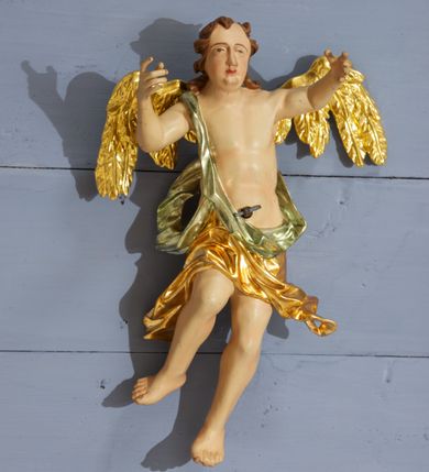 Zdjęcie nr 11: Drewniany, polichromowany na niebiesko strop, na planie ośmioboku, ujęty profilowaną ramą. W jego centrum grupa Koronacji Marii w glorii promienistej. W środku grupy figura Matki Boskiej na tle opaski dekorowanej kwiatami. Maria ukazana frontalnie, w kontrapoście, z rękami złożonymi w geście modlitwy. Twarz ma pociągłą, szczupłą, o młodzieńczych rysach, okoloną długimi włosami, upiętymi z tyłu głowy. Ubrana jest w srebrzoną suknię oraz złocony płaszcz narzucony na ramiona i zawinięty na lewej nodze, na głowie ma koronę zamkniętą. Marię flankują dwie banderole z napisem: „FIAT”. Po jej prawej znacznie większa figura Chrystusa, ukazanego frontalnie, w pozycji siedzącej, z głową skierowaną do wewnątrz; jego lewa ręka spoczywa na piersi, prawa jest ugięta i uniesiona w geście wskazującym. Twarz ma pociągłą, szczupłą, okoloną brodą skręconą w dwa pukle, oraz kręconymi włosami. Chrystus przewiązany jest w partii bioder złoconym płaszczem otaczającym postać i odsłaniającym lewą nogę. Jego ciało w odsłoniętych partiach, ma delikatnie zarysowaną muskulaturę, z zaznaczonymi śladami męki. Po lewej stronie Marii znacznie większa figura Boga Ojca, ukazanego frontalnie, w pozycji siedzącej. Lewą ręką przytrzymuje jabłko królewskie, w dłoni dzierży berło, prawą wyciąga w geście błogosławieństwa. Twarz ma pociągłą, o starczych rysach, okoloną długą, kręconą brodą opadającą na pierś oraz krótkimi włosami. Ubrany jest w obficie drapowaną srebrzoną tunikę, przepasaną w talii oraz złocony płaszcz z dekoracyjną, kameryzowaną lamówką, zapięty na piersi i opadający na boki, z zawiniętym fragmentem tkaniny na lewej nodze. Nad postaciami nadlatująca gołębica Ducha Świętego w glorii promienistej z banderolą z napisem: „FIAT”. Grupa na tle trzystrefowej glorii promienistej dekorowanej gwiazdami i uskrzydlonymi główkami anielskimi. Glorię z grupą Koronacji otacza dwunastu aniołów, ułożonych naprzemiennie w cztery pary muzykujących postaci (ze skrzypcami, wiolonczelą, gitarą, trąbką, harfą) z czterema aniołami podtrzymującymi tace z symbolicznymi przedmiotami (różaniec, wieniec laurowy, chleb (?), dyscyplina). Strop dekorowany jest w całości gwiazdami i uskrzydlonymi główkami anielskimi. Figury w partiach ciała polichromowane są naturalistycznie, ich szaty są złocone, srebrzone i laserowane; atrybuty są srebrzone. 

