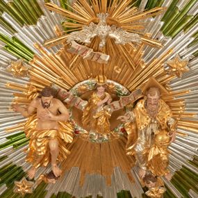 Zdjęcie nr 1: Drewniany, polichromowany na niebiesko strop, na planie ośmioboku, ujęty profilowaną ramą. W jego centrum grupa Koronacji Marii w glorii promienistej. W środku grupy figura Matki Boskiej na tle opaski dekorowanej kwiatami. Maria ukazana frontalnie, w kontrapoście, z rękami złożonymi w geście modlitwy. Twarz ma pociągłą, szczupłą, o młodzieńczych rysach, okoloną długimi włosami, upiętymi z tyłu głowy. Ubrana jest w srebrzoną suknię oraz złocony płaszcz narzucony na ramiona i zawinięty na lewej nodze, na głowie ma koronę zamkniętą. Marię flankują dwie banderole z napisem: „FIAT”. Po jej prawej znacznie większa figura Chrystusa, ukazanego frontalnie, w pozycji siedzącej, z głową skierowaną do wewnątrz; jego lewa ręka spoczywa na piersi, prawa jest ugięta i uniesiona w geście wskazującym. Twarz ma pociągłą, szczupłą, okoloną brodą skręconą w dwa pukle, oraz kręconymi włosami. Chrystus przewiązany jest w partii bioder złoconym płaszczem otaczającym postać i odsłaniającym lewą nogę. Jego ciało w odsłoniętych partiach, ma delikatnie zarysowaną muskulaturę, z zaznaczonymi śladami męki. Po lewej stronie Marii znacznie większa figura Boga Ojca, ukazanego frontalnie, w pozycji siedzącej. Lewą ręką przytrzymuje jabłko królewskie, w dłoni dzierży berło, prawą wyciąga w geście błogosławieństwa. Twarz ma pociągłą, o starczych rysach, okoloną długą, kręconą brodą opadającą na pierś oraz krótkimi włosami. Ubrany jest w obficie drapowaną srebrzoną tunikę, przepasaną w talii oraz złocony płaszcz z dekoracyjną, kameryzowaną lamówką, zapięty na piersi i opadający na boki, z zawiniętym fragmentem tkaniny na lewej nodze. Nad postaciami nadlatująca gołębica Ducha Świętego w glorii promienistej z banderolą z napisem: „FIAT”. Grupa na tle trzystrefowej glorii promienistej dekorowanej gwiazdami i uskrzydlonymi główkami anielskimi. Glorię z grupą Koronacji otacza dwunastu aniołów, ułożonych naprzemiennie w cztery pary muzykujących postaci (ze skrzypcami, wiolonczelą, gitarą, trąbką, harfą) z czterema aniołami podtrzymującymi tace z symbolicznymi przedmiotami (różaniec, wieniec laurowy, chleb (?), dyscyplina). Strop dekorowany jest w całości gwiazdami i uskrzydlonymi główkami anielskimi. Figury w partiach ciała polichromowane są naturalistycznie, ich szaty są złocone, srebrzone i laserowane; atrybuty są srebrzone. 

