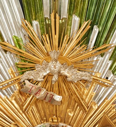 Zdjęcie nr 2: Drewniany, polichromowany na niebiesko strop, na planie ośmioboku, ujęty profilowaną ramą. W jego centrum grupa Koronacji Marii w glorii promienistej. W środku grupy figura Matki Boskiej na tle opaski dekorowanej kwiatami. Maria ukazana frontalnie, w kontrapoście, z rękami złożonymi w geście modlitwy. Twarz ma pociągłą, szczupłą, o młodzieńczych rysach, okoloną długimi włosami, upiętymi z tyłu głowy. Ubrana jest w srebrzoną suknię oraz złocony płaszcz narzucony na ramiona i zawinięty na lewej nodze, na głowie ma koronę zamkniętą. Marię flankują dwie banderole z napisem: „FIAT”. Po jej prawej znacznie większa figura Chrystusa, ukazanego frontalnie, w pozycji siedzącej, z głową skierowaną do wewnątrz; jego lewa ręka spoczywa na piersi, prawa jest ugięta i uniesiona w geście wskazującym. Twarz ma pociągłą, szczupłą, okoloną brodą skręconą w dwa pukle, oraz kręconymi włosami. Chrystus przewiązany jest w partii bioder złoconym płaszczem otaczającym postać i odsłaniającym lewą nogę. Jego ciało w odsłoniętych partiach, ma delikatnie zarysowaną muskulaturę, z zaznaczonymi śladami męki. Po lewej stronie Marii znacznie większa figura Boga Ojca, ukazanego frontalnie, w pozycji siedzącej. Lewą ręką przytrzymuje jabłko królewskie, w dłoni dzierży berło, prawą wyciąga w geście błogosławieństwa. Twarz ma pociągłą, o starczych rysach, okoloną długą, kręconą brodą opadającą na pierś oraz krótkimi włosami. Ubrany jest w obficie drapowaną srebrzoną tunikę, przepasaną w talii oraz złocony płaszcz z dekoracyjną, kameryzowaną lamówką, zapięty na piersi i opadający na boki, z zawiniętym fragmentem tkaniny na lewej nodze. Nad postaciami nadlatująca gołębica Ducha Świętego w glorii promienistej z banderolą z napisem: „FIAT”. Grupa na tle trzystrefowej glorii promienistej dekorowanej gwiazdami i uskrzydlonymi główkami anielskimi. Glorię z grupą Koronacji otacza dwunastu aniołów, ułożonych naprzemiennie w cztery pary muzykujących postaci (ze skrzypcami, wiolonczelą, gitarą, trąbką, harfą) z czterema aniołami podtrzymującymi tace z symbolicznymi przedmiotami (różaniec, wieniec laurowy, chleb (?), dyscyplina). Strop dekorowany jest w całości gwiazdami i uskrzydlonymi główkami anielskimi. Figury w partiach ciała polichromowane są naturalistycznie, ich szaty są złocone, srebrzone i laserowane; atrybuty są srebrzone. 

