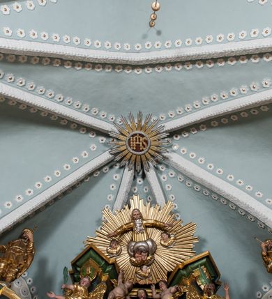 Zdjęcie nr 9: Nastawa ołtarzowa architektoniczna, trójosiowa z bramkami, dwukondygnacyjna, na dwustrefowym cokole. Ołtarz kamienny, prostopadłościenny, w drewnianej obudowie. Antepedium w formie wydłużonego, leżącego prostokąta, w polu obraz Ostatniej Wieczerzy. Mensa drewniana. Osie nastawy wydzielone parą półfilarów ujętych dwiema parami kolumn o kapitelach kompozytowych i skręconych trzonach. Dźwigają one pełne belkowanie silnie wyłamane na osi filarów, z mocno wysuniętym gzymsem, na skraju belkowania przerwany półkolisty przyczółek zwrócony na zewnątrz, na nim cokoły z figurami św. Władysława i św. Stefana. Na tle filarów ustawione figury św. Augustyna i św. Wojciecha, na bramkach rzeźby św. Marcina i św. Jana Jałmużnika. W polu głównym głęboka nisza w formie kwadratu zamkniętego łukiem falistym nadwieszonym, wewnątrz rzeźbiarska scena „Zabójstwa św. Stanisława”. Druga kondygnacja ujęta półfilarami, na tle których znajdują się anioły-kariatydy siedzące na cokołach z wolutami, podtrzymujące imposty. W polu prześwit w formie stojącego prostokąta z wpisanym krzyżem w kształcie litery „X”, przed którym znajduje się figura św. Andrzeja. Całość zwieńczona półpostacią Boga Ojca wśród obłoków i uskrzydlonych główek anielskich w glorii promienistej. Struktura obficie dekorowana ornamentem roślinnym, w partii pierwszej i drugiej kondygnacji uszy utworzone z akantu i wstęgi. Ołtarz flankują dodatkowo dwie pary wolnostojących półfilarów z półkolumnami o skręconych trzonach przed nimi, stojących na dwustrefowych cokołach, dźwigających imposty z figurami. Na zewnętrznej, niższej parze znajdują się figury św. Jana Ewangelisty i św. Jana Chrzciciela, na wewnętrznej, wyższej parze – św. Piotra i św. Pawła. Struktura polichromowana w sposób naśladujący marmoryzację w kolorze niebiesko-szarym, z zielonymi profilami oraz złoconymi kolumnami, profilami i ornamentyką.


