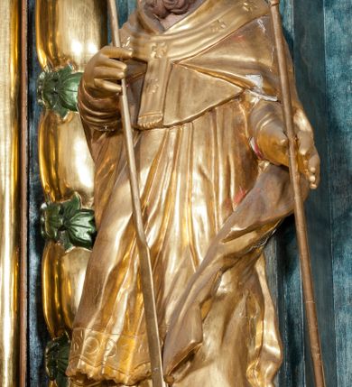 Zdjęcie nr 26: Nastawa ołtarzowa architektoniczna, trójosiowa z bramkami, dwukondygnacyjna, na dwustrefowym cokole. Ołtarz kamienny, prostopadłościenny, w drewnianej obudowie. Antepedium w formie wydłużonego, leżącego prostokąta, w polu obraz Ostatniej Wieczerzy. Mensa drewniana. Osie nastawy wydzielone parą półfilarów ujętych dwiema parami kolumn o kapitelach kompozytowych i skręconych trzonach. Dźwigają one pełne belkowanie silnie wyłamane na osi filarów, z mocno wysuniętym gzymsem, na skraju belkowania przerwany półkolisty przyczółek zwrócony na zewnątrz, na nim cokoły z figurami św. Władysława i św. Stefana. Na tle filarów ustawione figury św. Augustyna i św. Wojciecha, na bramkach rzeźby św. Marcina i św. Jana Jałmużnika. W polu głównym głęboka nisza w formie kwadratu zamkniętego łukiem falistym nadwieszonym, wewnątrz rzeźbiarska scena „Zabójstwa św. Stanisława”. Druga kondygnacja ujęta półfilarami, na tle których znajdują się anioły-kariatydy siedzące na cokołach z wolutami, podtrzymujące imposty. W polu prześwit w formie stojącego prostokąta z wpisanym krzyżem w kształcie litery „X”, przed którym znajduje się figura św. Andrzeja. Całość zwieńczona półpostacią Boga Ojca wśród obłoków i uskrzydlonych główek anielskich w glorii promienistej. Struktura obficie dekorowana ornamentem roślinnym, w partii pierwszej i drugiej kondygnacji uszy utworzone z akantu i wstęgi. Ołtarz flankują dodatkowo dwie pary wolnostojących półfilarów z półkolumnami o skręconych trzonach przed nimi, stojących na dwustrefowych cokołach, dźwigających imposty z figurami. Na zewnętrznej, niższej parze znajdują się figury św. Jana Ewangelisty i św. Jana Chrzciciela, na wewnętrznej, wyższej parze – św. Piotra i św. Pawła. Struktura polichromowana w sposób naśladujący marmoryzację w kolorze niebiesko-szarym, z zielonymi profilami oraz złoconymi kolumnami, profilami i ornamentyką.


