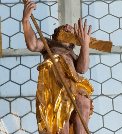 Zdjęcie nr 64: Nastawa ołtarzowa architektoniczna, trójosiowa z bramkami, dwukondygnacyjna, na dwustrefowym cokole. Ołtarz kamienny, prostopadłościenny, w drewnianej obudowie. Antepedium w formie wydłużonego, leżącego prostokąta, w polu obraz Ostatniej Wieczerzy. Mensa drewniana. Osie nastawy wydzielone parą półfilarów ujętych dwiema parami kolumn o kapitelach kompozytowych i skręconych trzonach. Dźwigają one pełne belkowanie silnie wyłamane na osi filarów, z mocno wysuniętym gzymsem, na skraju belkowania przerwany półkolisty przyczółek zwrócony na zewnątrz, na nim cokoły z figurami św. Władysława i św. Stefana. Na tle filarów ustawione figury św. Augustyna i św. Wojciecha, na bramkach rzeźby św. Marcina i św. Jana Jałmużnika. W polu głównym głęboka nisza w formie kwadratu zamkniętego łukiem falistym nadwieszonym, wewnątrz rzeźbiarska scena „Zabójstwa św. Stanisława”. Druga kondygnacja ujęta półfilarami, na tle których znajdują się anioły-kariatydy siedzące na cokołach z wolutami, podtrzymujące imposty. W polu prześwit w formie stojącego prostokąta z wpisanym krzyżem w kształcie litery „X”, przed którym znajduje się figura św. Andrzeja. Całość zwieńczona półpostacią Boga Ojca wśród obłoków i uskrzydlonych główek anielskich w glorii promienistej. Struktura obficie dekorowana ornamentem roślinnym, w partii pierwszej i drugiej kondygnacji uszy utworzone z akantu i wstęgi. Ołtarz flankują dodatkowo dwie pary wolnostojących półfilarów z półkolumnami o skręconych trzonach przed nimi, stojących na dwustrefowych cokołach, dźwigających imposty z figurami. Na zewnętrznej, niższej parze znajdują się figury św. Jana Ewangelisty i św. Jana Chrzciciela, na wewnętrznej, wyższej parze – św. Piotra i św. Pawła. Struktura polichromowana w sposób naśladujący marmoryzację w kolorze niebiesko-szarym, z zielonymi profilami oraz złoconymi kolumnami, profilami i ornamentyką.


