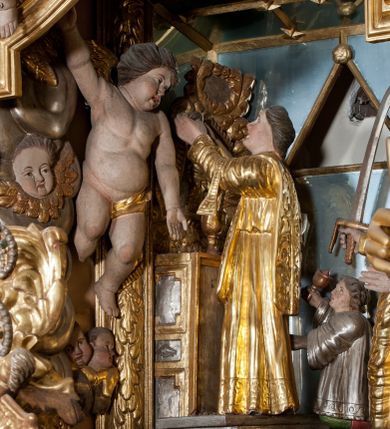 Zdjęcie nr 1: W głębokiej wnęce wyłożonej z trzech stron lustrami znajduje się grupa figuralna ze sceną zabójstwa św. Stanisława. Przed złoconym ołtarzem ustawionym na dwustopniowej podstawie figura św. Stanisława ukazana z lewego profilu w momencie podniesienia, z hostią w dłoniach. Święty jest ubrany w albę i ornat, z manipularzem na przedramieniu. U jego prawego boku, na najniższym stopniu klęczy ministrant ubrany w  komżę z uniesioną ręką, w której trzyma dzwonek. Za ich plecami figura króla Bolesława Szczodrego ustawiona na dwustopniowym postumencie, zwrócona w trzech czwartych w lewo, z uniesionym mieczem trzymanym w prawej ręce. Król jest ubrany w tunikę przewiązaną w pasie, płaszcz królewski i wysokie buty, na głowie ma koronę otwartą. Polichromia naturalistyczna w partiach ciała, szaty złocone i srebrzone.