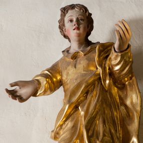 Zdjęcie nr 1: Rzeźba drążona, ustawiona jest frontalnie, w kontrapoście, z lewą ręką wyciągniętą do przodu, prawą w bok. Święty ma pełną twarz, o młodzieńczych rysach, dużych oczach, zadartym nosie, pełnych, rozchylonych ustach, okoloną krótkimi, kręconymi włosami, opadającymi na tył głowy i kark. Ubrany jest w przylegającą do ciała tunikę z kołnierzykiem oraz płaszcz przerzucony przez lewe ramię i opasujący korpus. Polichromia naturalistyczna w odsłoniętych partiach ciała, szaty pozłocone.