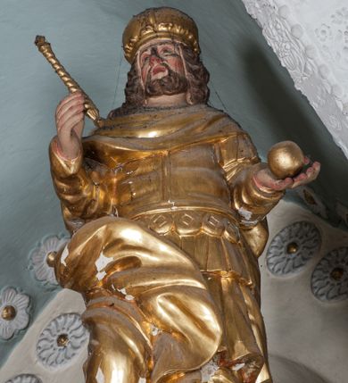 Zdjęcie nr 1: Figura ustawiona jest na rzeźbionym obłoku, zwrócona frontalnie, w kontrapoście, w lewej, wyciągniętej w bok ręce trzyma kulę (jabłko królewskie?), w prawej, wysuniętej w przód – berło. Twarz świętego kwadratowa, z oczami skierowanymi w górę, małym nosem i rozchylonymi ustami, okolona krótką brodą oraz sięgającymi ramion, kręconymi włosami. Stefan jest ubrany w suknię sięgającą kolan, zbroję torsową oraz płaszcz zawinięty na prawej nodze, spodnie i wysokie buty, na głowie ma koronę zamkniętą. Polichromia naturalistyczna w odsłoniętych partiach ciała, strój i atrybuty pozłacane.