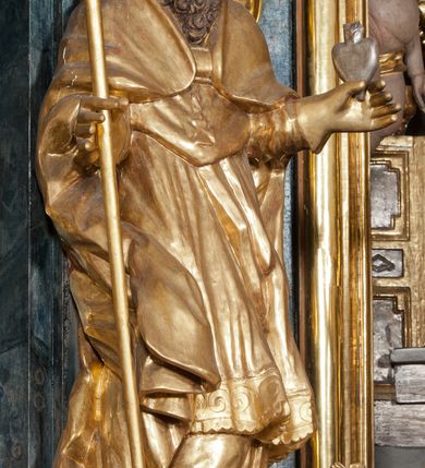 Zdjęcie nr 2: Rzeźba ścięta z tyłu, ustawiona jest na obłoku, zwrócona frontalnie, o esowato wygiętej sylwetce, z rękoma rozłożonymi na boki. Święty w lewej dłoni trzyma gorejące serce, w prawej pastorał. Twarz ma pociągłą o prostym nosie, głęboko rzeźbionej górnej powiece oraz szerokich, rozchylonych ustach, okoloną gęstą brodą, silnie kręconą oraz krótkimi włosami. Ubrany jest w albę, komżę, mucet i kapę, na piersi ma krzyż pektoralny, na głowie infułę, na dłoniach zaś rękawiczki. Polichromia naturalistyczna w odsłoniętych partiach ciała, strój i pastorał pozłocone, serce posrebrzone.