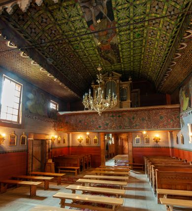 Zdjęcie nr 13: Polichromia pokrywa praktycznie całe wnętrze kościoła wraz z przedsionkiem. Przy wejściu, na stropie pod wieżą znajduje się polichromia patronowa. Jest wielobrawna, z motywami architektonicznymi, geometrycznymi, roślinno-kwiatowymi i figuralnymi – jeleniami, parami gołąbków, orłami, smokami. Wśród nich postać jeźdźca z kopią i grupa ludzi udających się na polowanie, poniżej których napis „Odbudowę kościoła, urządzenie wnętrza i rekonstrukcję dokonano staraniem Ks(iędza) Andrzeja Braszki / w czasie od lipca 1932 do grudnia r(oku) (19)39. / Pracę rozpoczął Władysław Cichoń + Skończył Adam Stalony-Dobrzański z Eugeniuszem Pisarkiem”. W polichromii przedsionka przeważają kolory  biały, czerwony, zielony, niebieski, żółty i czarny. Ponad wejściem do nawy napis  „ZACZNIJCIE / WARGI NASZE / CHWALIĆ PANNĘ / ŚWIĘTĄ / ZACZNIJCIE OPOWIADAĆ / CZEŚĆ JEJ NIEPOJĘTĄ”  i po drugieh stronie „PRZYBĄDŹ NAM. MIŁOŚCIWA PANI / KU POMOCY / A WYBAW NAS / Z RĄK POTĘŻNYCH / NIEPRZYJACIÓŁ MOCY”. Poniżej „CHWAŁA OJCU I SYNOWI JEGO PRZEDWIECZNEMU”.
W prezbiterium na ścianie i na suficie imitacja kasetonów z rozetami z przewagą koloru zielonego uzupełnionego czerwonym na ścianie i czarnym oraz bladożółtym na stropie. W centrum sufitu postać Matki Boskiej z Dzieciątkiem na lewym ramieniu, za którymi dwaj aniołowie skłaniający głowy. Maria ma poważną twarz o delikatnych rysach, ciemne oczy i wąski nos, na głowie otwartą koronę, wokół niej nimb. Jest ubrana w jasną sukienkę i intensywnie niebieski płaszcz. Dzieciątko prawą ręką błogosławi, lewą trzyma rękę Marii. Ma owalną, delikatną twarz, a na sobie jasną tunikę i zamkniętą koronę. 
W nawie, pośród takich samych kasetonów jak w prezbiterium, na sklepieniu wyobrażenie św. Michała Archanioła zabijającego szatana. Ponad nim postać anioła splatającego dłonie pod brodą. Archanioł spogląda pod stopy, w prawej ręce trzyma skierowany ostrzem w stronę potwora miecz, lewą ma opuszczoną do boku. Ma na sobie zieloną tunikę przewiązaną szerokim, góralskim pasem i czerwony płaszcz. Jasne postrzępione plamy ponad jego plecami sugerują skrzydła. Anioł powyżej jest ubrany w czerwoną sukienkę, nad nim płynnie uchodzą w górę ulistnione linie. Na ścianach nawy, pod linią stropu, rząd klęczących aniołów między kwitnącymi kwiatami. Każdy jest ubrany w zielonożółtą sukienkę i sandały, ma włosy do ramion i złoty nimb. Skrzydła z różnie ułożonych piór są wielobarwne. Anioły klęczą na linii ornamentu, ściana poniżej jest jasnoniebieska, z napisem powyżej opisanych przedstawień. 
Na skośnych fragmentach stropu imitacja drobniejszych kasetonów o falistym zarysie, wypełnionych krzyżami równoramiennymi. Wszystkie ciemnożółte, większość na czarnym tle, niektóre na tle zielonym tworzą kształt rombów. Na krawędzi motywy geometryczne, które mogą sugerować płonące serca. 
Na parapecie chóru fragmenty dawnej polichromii o motywach liściasto-wiciowych z rozwiniętymi kwiatami i motywem żołędzia. Między nimi ludzka głowa. Malowidło utrzymane w dominującym kolorze brązu, z elementami zielonymi i czerwonymi. 
