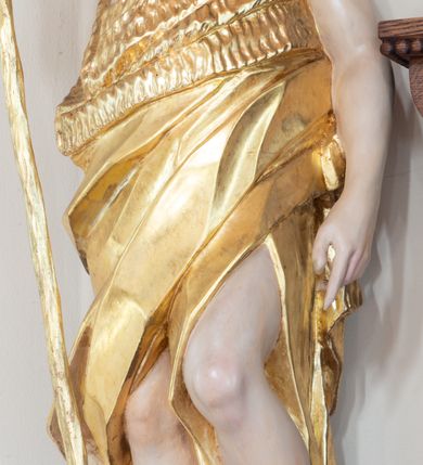 Zdjęcie nr 1: Święty ukazany frontalnie, z głową skierowaną w lewo, w prawej ręce trzyma laskę zakończoną krzyżem, lewą ma opuszczoną wzdłuż boku, lewą nogę opiera na rzeźbionym kamieniu, na którym stoi baranek. Twarz ma pociągłą, o migdałowatych oczach skierowanych w górę, prostym nosie i rozchylonych ustach, okoloną krótką, kręconą brodą oraz kręconymi włosami opadającymi na ramiona. Ubrany jest w melotę opasującą jego korpus i nogi, odsłaniającą część klatki piersiowej i ramiona oraz lewą nogę. Polichromia ciała naturalistyczna, włosy i broda brązowe, strój i laska złocone, baranek srebrzony. 