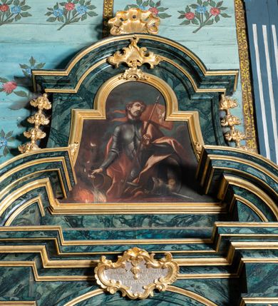 Zdjęcie nr 14: Nastawa architektoniczna, jednoosiowa, jednokondygnacyjna ze zwieńczeniem. Ołtarz prostopadłościenny, murowany, w drewnianej obudowie, z kamienną mensą. Antepedium ujęte profilowaną ramą, w polu malowana płycina w formie leżącego prostokąta o wklęsłych narożach, wypełniona różami, z akantowym kartuszem w centrum. W narożach przedstawienia ptaków na gałęziach. W polu kartusza scena męczeństwa św Wita, na tle pejzażu. Retabulum ustawione na dwustrefowym cokole, z wyłamanymi dwoma prostopadłościanami, w górnej części dekorowanymi rocaille'owymi płycinami. Nastawa ujęta parą zdwojonych pilastrów, o kanelowanych trzonach i kapitelach kompozytowych, dźwigających pełne belkowanie, wyłamane na ich osi, z architrawem przyjmującym nad polem środkowym formę łuku odcinkowego oraz fragmenty półkolistego, przerwanego przyczółka. W polu centralnym wnęka w kształcie stojącego prostokąta zamkniętego łukiem półkolistym nadwieszonym, ujęta profilowaną ramą, z obrazem św. Józefa z Dzieciątkiem. Nad nią, w polu belkowania rocaille'owy kartusz z napisem „QUIA VIRGO ELECTUS / VIRGO IN AEVUM / PERMANSIT”. Zwieńczenie w formie zbliżonej do trapezu, ujętego spływami wolutowymi, zamkniętego fragmentem gzymsu w formie łuku półkolistego nadwieszonego. Zwieńczenie zakończone rokokową muszlą i rocaille'm, flankowane kampanulami. W polu obraz św. Floriana w kształcie analogicznym do zwieńczenia, w profilowanej ramie. Struktura polichromowana na sposób imitujący marmoryzację w kolorach niebieskim i zielonym, profile i ornamentyka złocone, detal srebrzony. 



