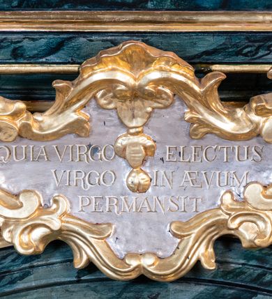 Zdjęcie nr 6: Nastawa architektoniczna, jednoosiowa, jednokondygnacyjna ze zwieńczeniem. Ołtarz prostopadłościenny, murowany, w drewnianej obudowie, z kamienną mensą. Antepedium ujęte profilowaną ramą, w polu malowana płycina w formie leżącego prostokąta o wklęsłych narożach, wypełniona różami, z akantowym kartuszem w centrum. W narożach przedstawienia ptaków na gałęziach. W polu kartusza scena męczeństwa św Wita, na tle pejzażu. Retabulum ustawione na dwustrefowym cokole, z wyłamanymi dwoma prostopadłościanami, w górnej części dekorowanymi rocaille'owymi płycinami. Nastawa ujęta parą zdwojonych pilastrów, o kanelowanych trzonach i kapitelach kompozytowych, dźwigających pełne belkowanie, wyłamane na ich osi, z architrawem przyjmującym nad polem środkowym formę łuku odcinkowego oraz fragmenty półkolistego, przerwanego przyczółka. W polu centralnym wnęka w kształcie stojącego prostokąta zamkniętego łukiem półkolistym nadwieszonym, ujęta profilowaną ramą, z obrazem św. Józefa z Dzieciątkiem. Nad nią, w polu belkowania rocaille'owy kartusz z napisem „QUIA VIRGO ELECTUS / VIRGO IN AEVUM / PERMANSIT”. Zwieńczenie w formie zbliżonej do trapezu, ujętego spływami wolutowymi, zamkniętego fragmentem gzymsu w formie łuku półkolistego nadwieszonego. Zwieńczenie zakończone rokokową muszlą i rocaille'm, flankowane kampanulami. W polu obraz św. Floriana w kształcie analogicznym do zwieńczenia, w profilowanej ramie. Struktura polichromowana na sposób imitujący marmoryzację w kolorach niebieskim i zielonym, profile i ornamentyka złocone, detal srebrzony. 


