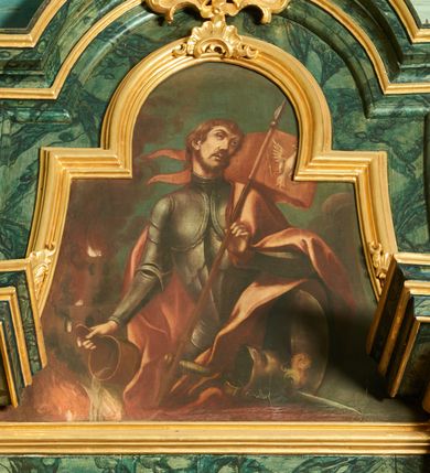 Zdjęcie nr 1: Obraz w formie zbliżonej do trapezu zamkniętego łukiem półkolistym nadwieszonym, o wklęsłych bokach. W centrum św. Florian ukazany w półpostaci, zwrócony w trzech czwartych w prawo, z głową skierowaną w przeciwną stronę. W lewej, ugiętej ręce trzyma drzewce czerwonego sztandaru z wizerunkiem białego orła, w prawej, wyciągniętej w bok trzyma cebrzyk, z którego wylewa wodę na płomienie. Twarz ma owalną, o niskim czole, małych okrągłych oczach, uniesionych brwiach, wąskim nosie i pełnych ustach; okoloną krótkimi, brązowymi włosami i brodą. Ubrany jest w metalową zbroję płytową, na lewy bok ma zarzucony czerwony, rozwiany płaszcz. Przed świętym, w prawym dolnym rogu obrazu leżą tarcza, miecz i hełm z pióropuszem. W lewej części obrazu, w tle ukazany płonący budynek. Święty przedstawiony na tle niebieskiego nieba z szarymi obłokami.  


