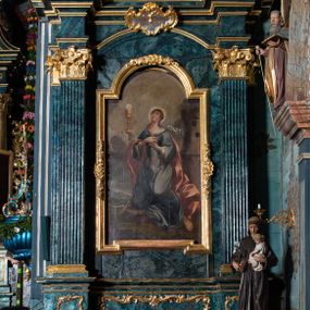 Zdjęcie nr 1: Nastawa architektoniczna, jednoosiowa, jednokondygnacyjna ze zwieńczeniem. Ołtarz prostopadłościenny, murowany, w drewnianej obudowie, z kamienną mensą. Antepedium ujęte profilowaną ramą, w polu malowana płycina w formie leżącego prostokąta o wklęsłych narożach, wypełniona różami, z akantowym kartuszem w centrum. W narożach przedstawienia ptaków na gałęziach. W polu kartusza scena ścięcia św. Barbary przez oprawcę, na tle pejzażu. Retabulum ustawione na dwustrefowym cokole, z wyłamanymi dwoma prostopadłościanami, w górnej części dekorowanym rocaille'owymi płycinami. Nastawa ujęta parą zdwojonych pilastrów, o kanelowanych trzonach i kapitelach kompozytowych, dźwigających pełne belkowanie, wyłamane na ich osi, z architrawem przyjmującym nad polem środkowym formę łuku odcinkowego oraz fragmenty półkolistego, przerwanego przyczółka. W polu centralnym wnęka w kształcie stojącego prostokąta zamkniętego łukiem półkolistym nadwieszonym, ujęta profilowaną ramą, z obrazem św. Barbary. Nad nią, w polu belkowania rocaille'owy kartusz z napisem „IT DE / NOCTE SURREXIT DEDIT / CIBARIA ANCIRIS / SUIS”. Zwieńczenie w formie zbliżonej do trapezu, ujętego spływami wolutowymi, zamkniętego fragmentem gzymsu w kształcie łuku półkolistego nadwieszonego. Zwieńczenie zakończone rokokową muszlą i rocaille'm, flankowane kampanulami. W polu obraz pokutującej św. Marii Magdaleny w kształcie analogicznym do zwieńczenia, w profilowanej ramie. Struktura polichromowana na sposób imitujący marmoryzację w kolorach niebieskim i zielonym, profile i ornamentyka złocone, detal srebrzony. 




