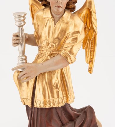 Zdjęcie nr 6: Pełnoplastyczne figury klęczących na jedno kolano aniołów, ustawionych na niskich podstawach. Postacie ukazane są z profilu, z głowami skierowanymi frontalnie. Na ugiętych kolanach trzymają srebrzone lichtarze, przytrzymując je obiema rękami, z boku i od spodu. Twarze mają podłużne, trójkątne, o dużych, migdałowatych, opadających oczach, prostych nosach i wąskich ustach, okolone silnie kręconymi włosami, układającymi się po bokach głowy, a nad czołem tworzące czub. Ubrane są w długie ciemnoczerwone suknie spodnie i złocone suknie wierzchnie z kołnierzykami, sięgające kolan, z podwiniętymi rękawami, przepasane w talii szarfami. Skrzydła mają małe, złocone, złożone po bokach postaci. Polichromia ciała naturalistyczna. 



