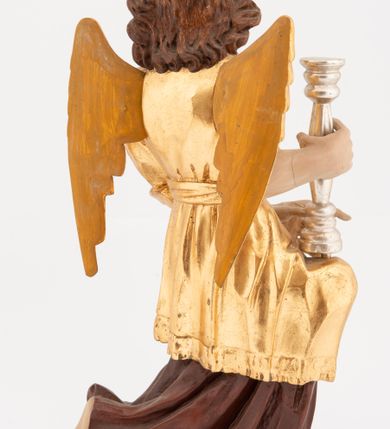 Zdjęcie nr 9: Pełnoplastyczne figury klęczących na jedno kolano aniołów, ustawionych na niskich podstawach. Postacie ukazane są z profilu, z głowami skierowanymi frontalnie. Na ugiętych kolanach trzymają srebrzone lichtarze, przytrzymując je obiema rękami, z boku i od spodu. Twarze mają podłużne, trójkątne, o dużych, migdałowatych, opadających oczach, prostych nosach i wąskich ustach, okolone silnie kręconymi włosami, układającymi się po bokach głowy, a nad czołem tworzące czub. Ubrane są w długie ciemnoczerwone suknie spodnie i złocone suknie wierzchnie z kołnierzykami, sięgające kolan, z podwiniętymi rękawami, przepasane w talii szarfami. Skrzydła mają małe, złocone, złożone po bokach postaci. Polichromia ciała naturalistyczna. 



