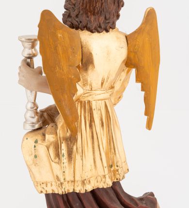 Zdjęcie nr 4: Pełnoplastyczne figury klęczących na jedno kolano aniołów, ustawionych na niskich podstawach. Postacie ukazane są z profilu, z głowami skierowanymi frontalnie. Na ugiętych kolanach trzymają srebrzone lichtarze, przytrzymując je obiema rękami, z boku i od spodu. Twarze mają podłużne, trójkątne, o dużych, migdałowatych, opadających oczach, prostych nosach i wąskich ustach, okolone silnie kręconymi włosami, układającymi się po bokach głowy, a nad czołem tworzące czub. Ubrane są w długie ciemnoczerwone suknie spodnie i złocone suknie wierzchnie z kołnierzykami, sięgające kolan, z podwiniętymi rękawami, przepasane w talii szarfami. Skrzydła mają małe, złocone, złożone po bokach postaci. Polichromia ciała naturalistyczna. 



