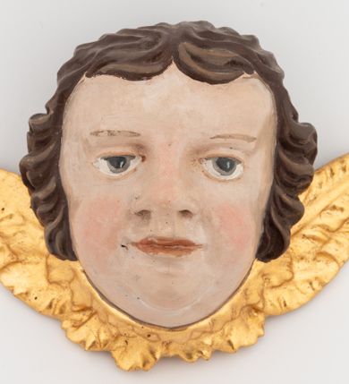 Zdjęcie nr 1: Rzeźby ścięte z tyłu. Głowy aniołków ujęte małymi, złoconymi skrzydełkami, rozłożonymi na boki. Twarze mają kwadratowe,  z wydatnymi brodami, o migdałowatych oczach, krótkich nosach o szerokich nozdrzach i wąskich, długich ustach; okolone są krótkimi, falowanymi, brązowymi włosami, z krótką, rozdzieloną na środku czoła grzywką. Polichromia ciała naturalistyczna. 

